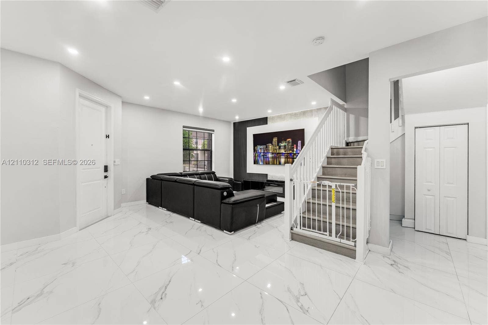 11524 SW 248th Lane, Homestead, FL 33032 Open floor plan featuring large-format stone-style tile flooring, recessed ceiling lighting, a floor-to-ceiling fireplace surround with stone-finish accent wall, and a staircase with white balusters
