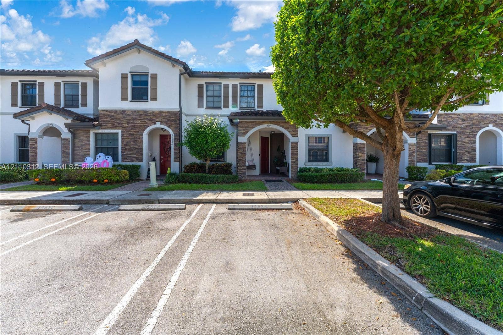 11524 SW 248th Lane, Homestead, FL 33032 Multi-unit exterior featuring stucco and stone-veneer siding, arched entryway detailing, tile roofing, and assigned parking spaces
