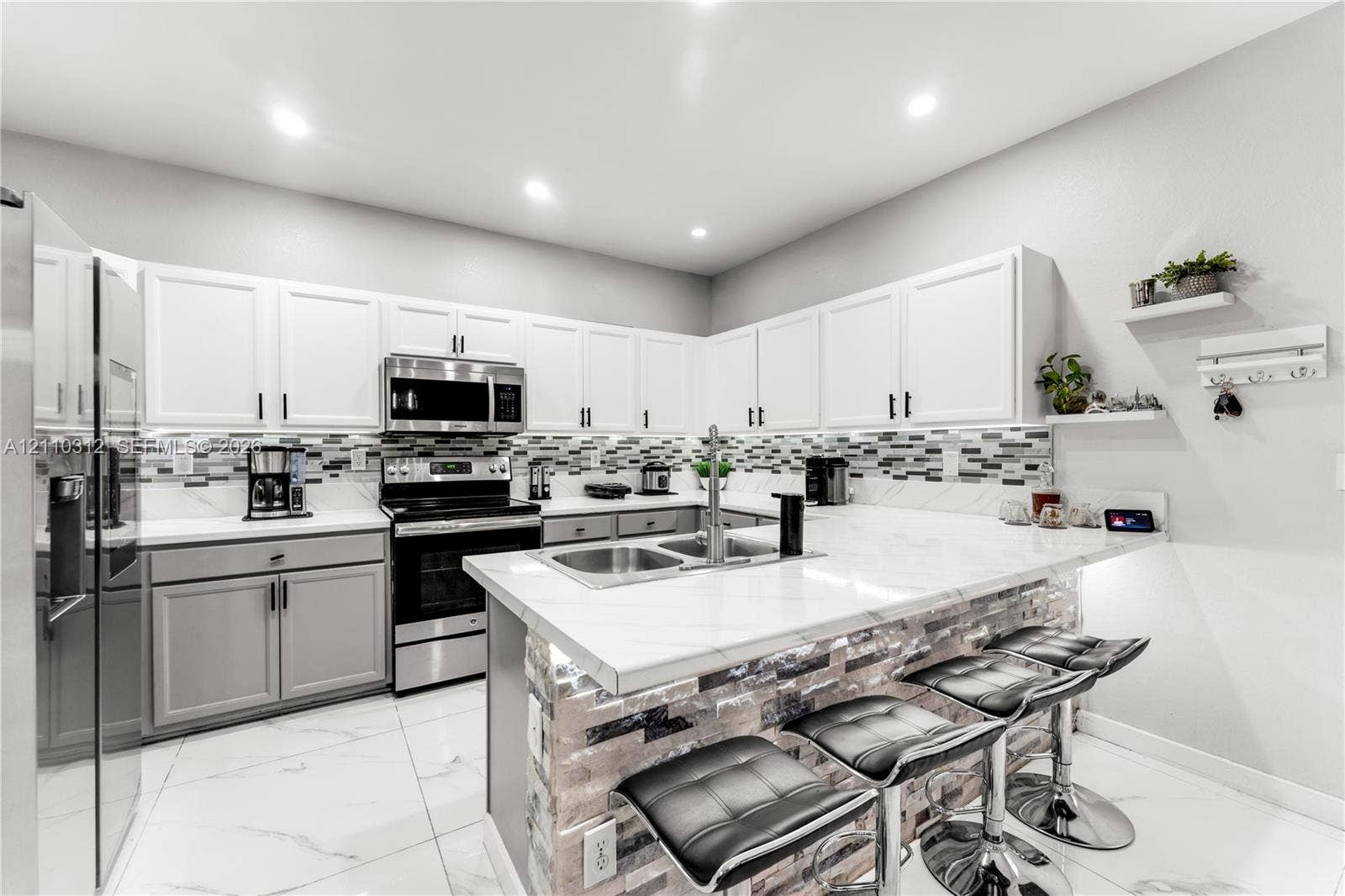 11524 SW 248th Lane, Homestead, FL 33032 Kitchen featuring white upper cabinetry, grey lower cabinetry, white stone-finish countertops, stainless steel appliances, and a tiled backsplash