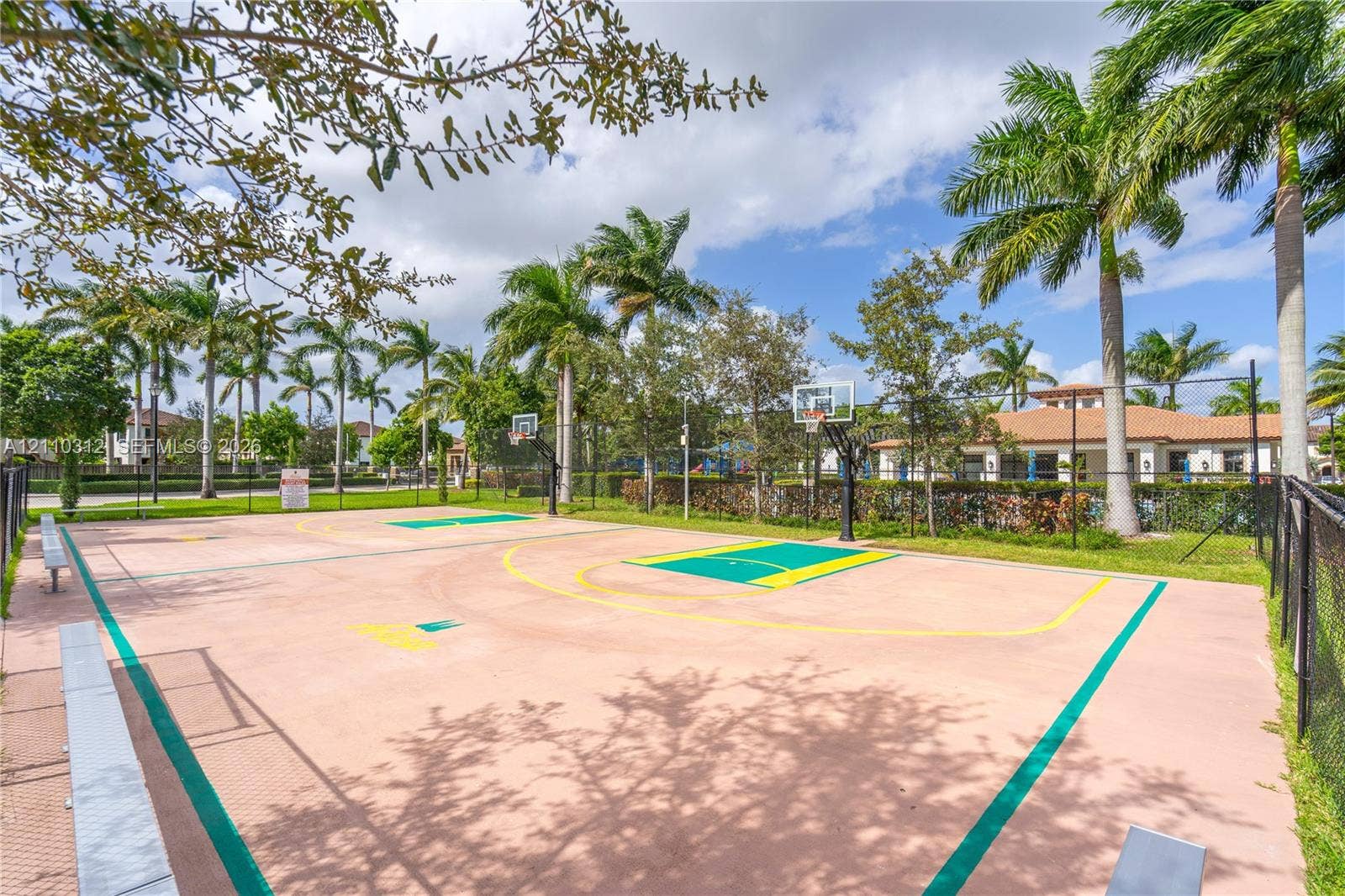 11524 SW 248th Lane, Homestead, FL 33032 Outdoor basketball court featuring paved surfacing, dual goals, and perimeter fencing, accented by palm trees and manicured landscaping