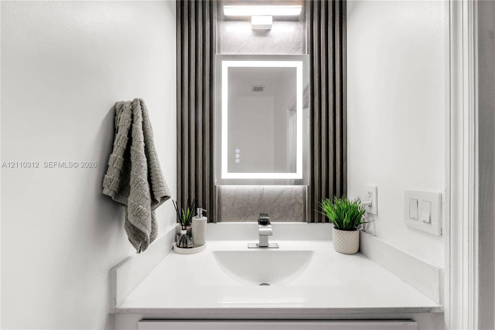 11524 SW 248th Lane, Homestead, FL 33032 Integrated vanity featuring a solid surface countertop, undermount sink, LED-lit vanity mirror, and decorative fluted wall paneling