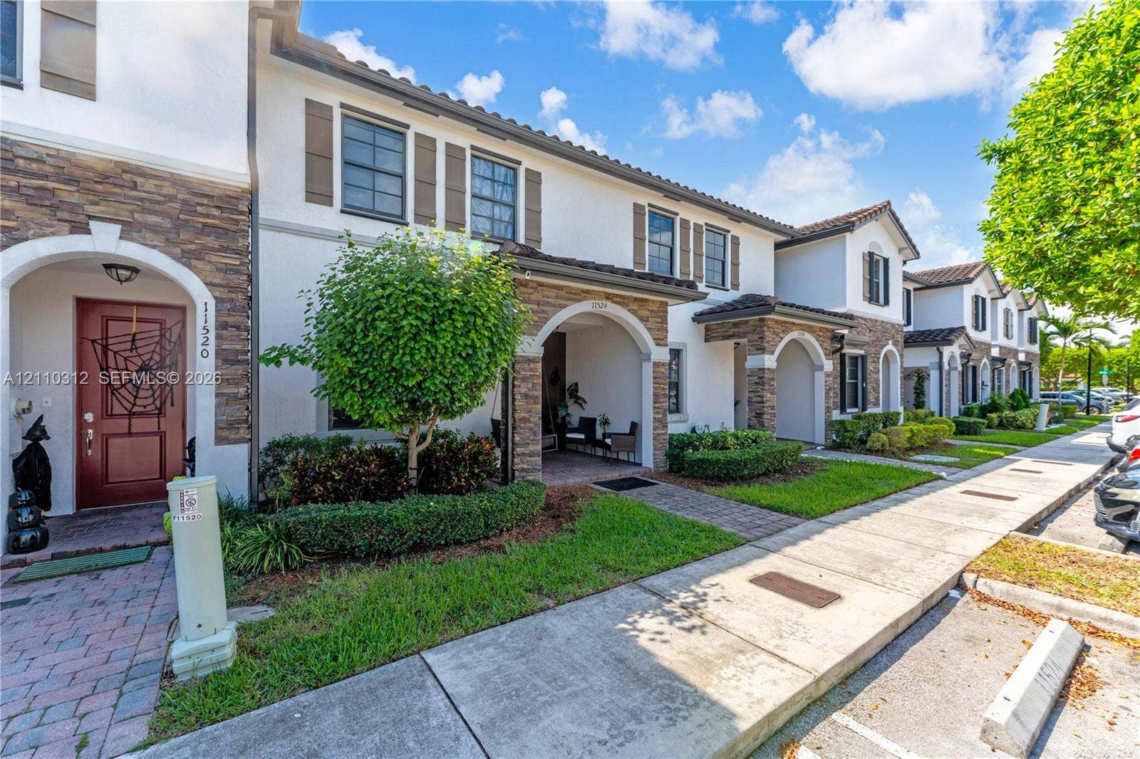 11524 SW 248th Lane, Homestead, FL 33032 Mediterranean-style exterior featuring smooth stucco facade, decorative stone veneer, arched entryway, brick-paver walkway, and dark-frame windows