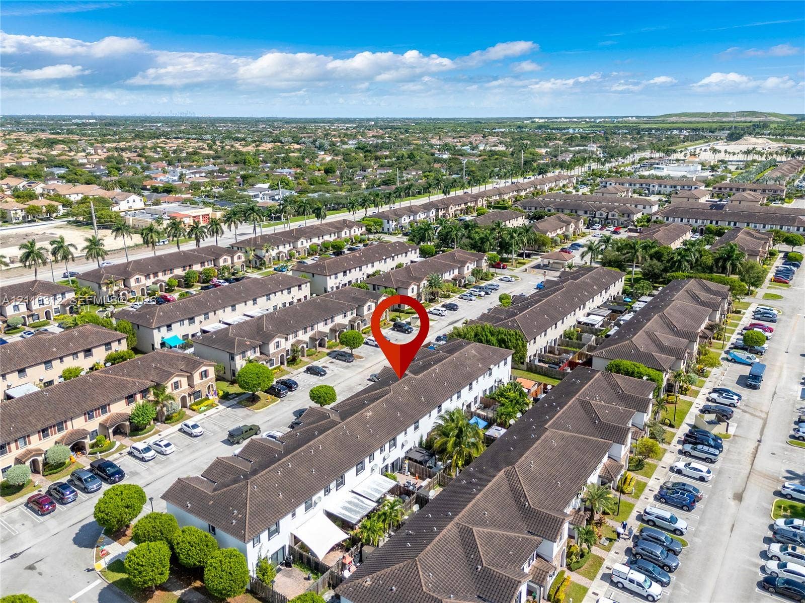 11524 SW 248th Lane, Homestead, FL 33032 Aerial perspective of a multi-unit residential complex featuring dark-toned tiled roofing, uniform architectural design, and integrated paved parking areas