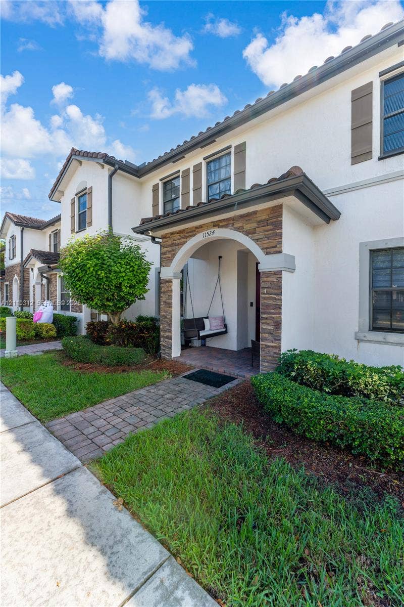 11524 SW 248th Lane, Homestead, FL 33032 Stucco exterior with stone veneer accents, arched covered entryway, paver walkway, and decorative window shutters