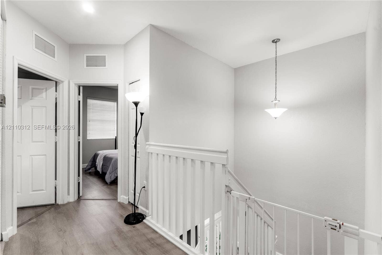 11524 SW 248th Lane, Homestead, FL 33032 Hallway featuring neutral wall tones, wood-finish flooring, a white spindle railing, and a pendant light fixture