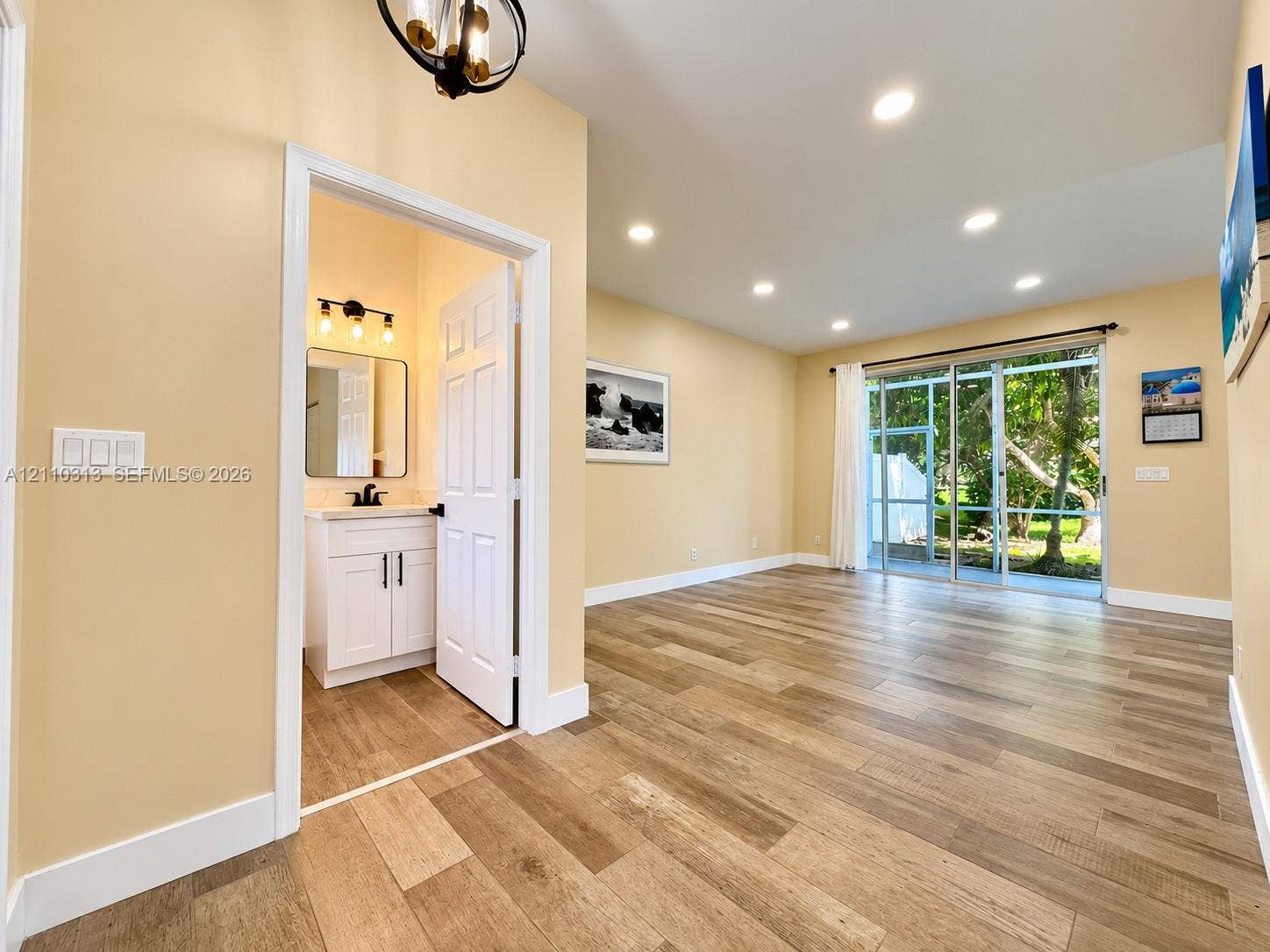 17731 SW 23rd Street, Miramar, FL 33029 Wood-finish tile flooring throughout with recessed lighting, floor-to-ceiling sliding glass doors, and a bathroom featuring a white vanity cabinet and matte black hardware