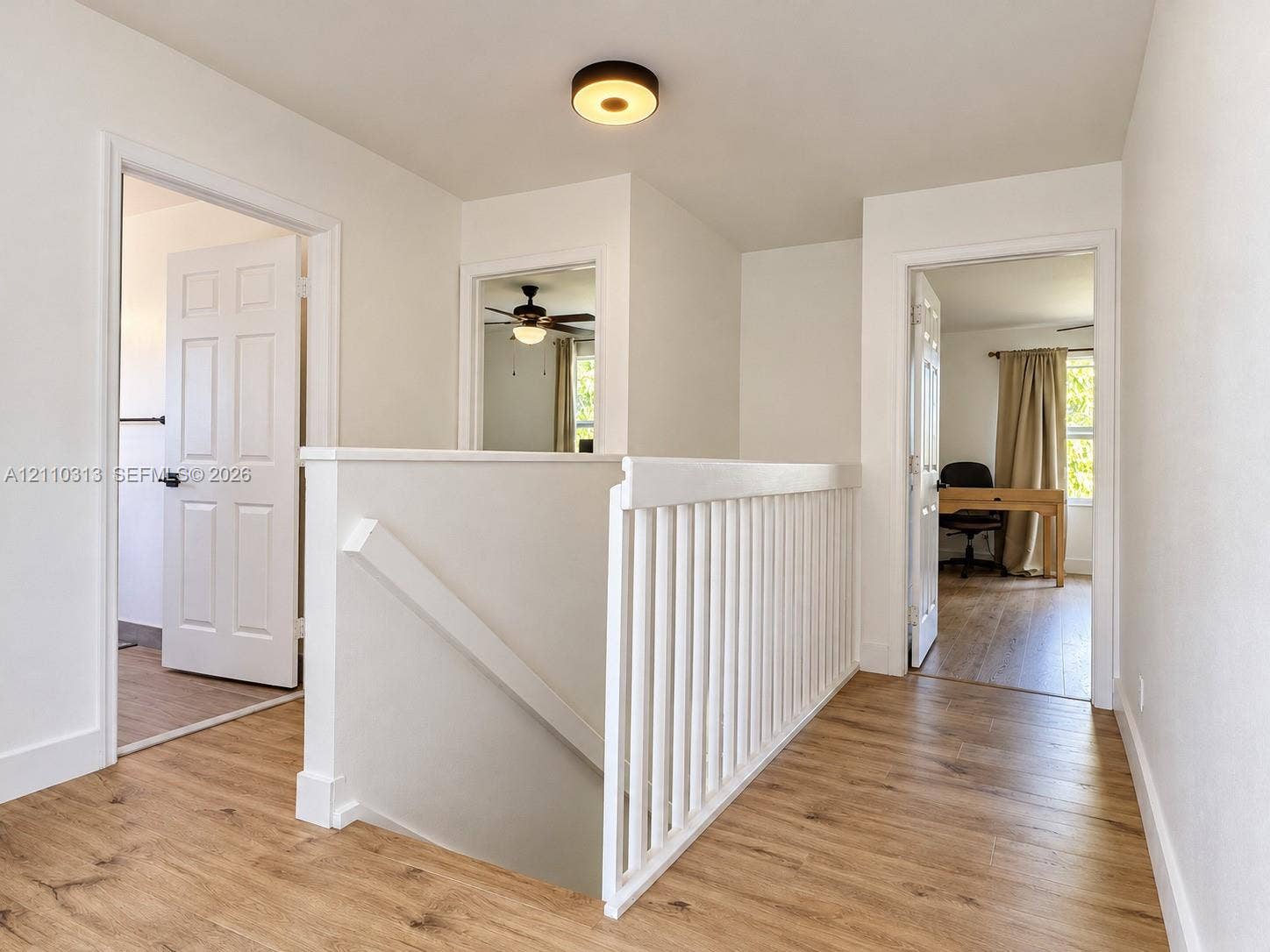 17731 SW 23rd Street, Miramar, FL 33029 Hallway featuring wood-finish flooring, a white wooden balustrade, and a flush-mount circular ceiling light fixture