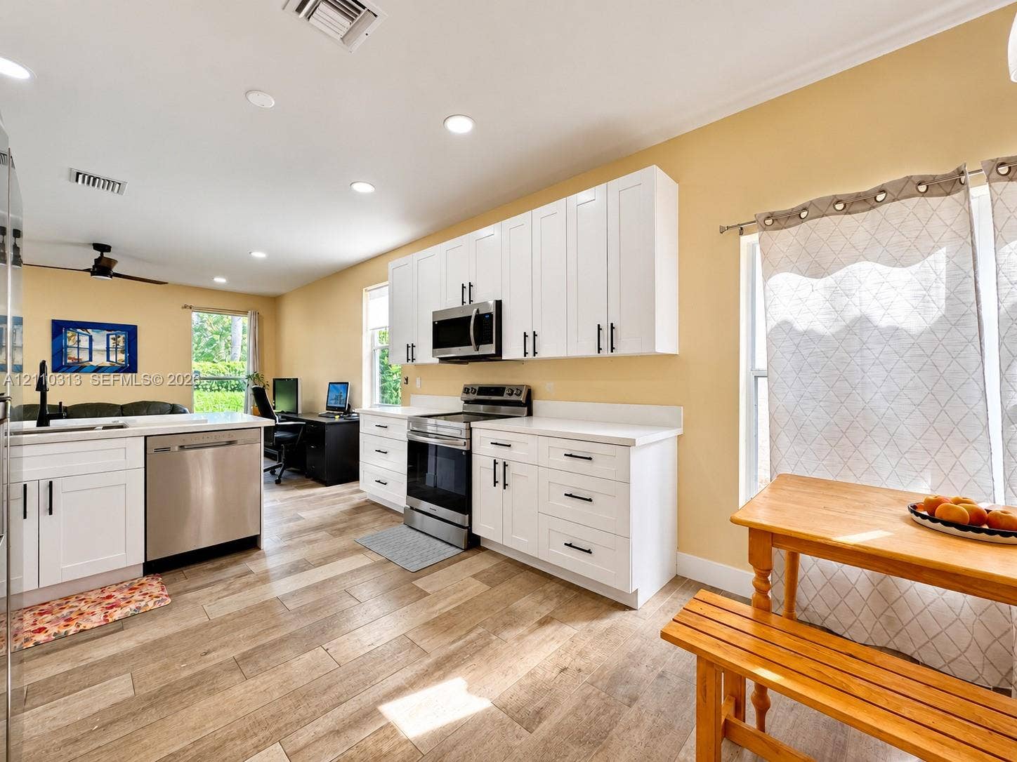 17731 SW 23rd Street, Miramar, FL 33029 Kitchen featuring white Shaker-style cabinetry, stainless steel appliances, solid-surface countertops, and wood-finish flooring