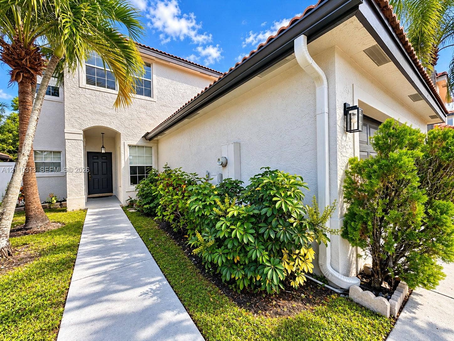 17731 SW 23rd Street, Miramar, FL 33029 Stucco exterior featuring a concrete walkway, multi-pane windows, terra cotta roof tiles, and an arched entryway