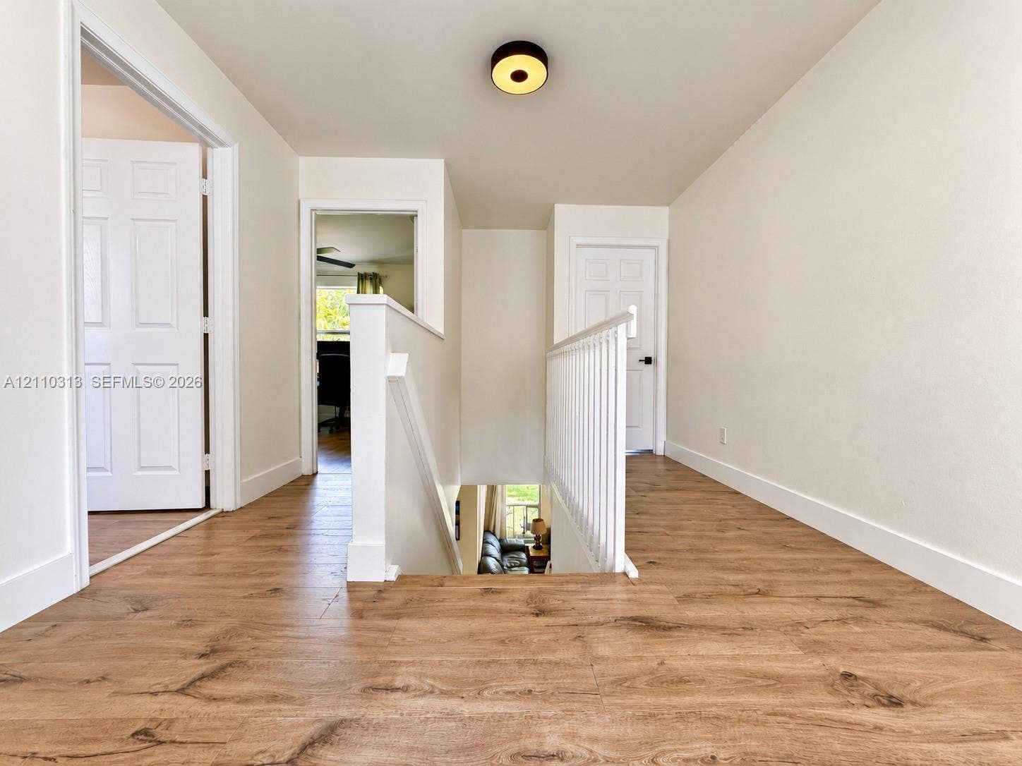 17731 SW 23rd Street, Miramar, FL 33029 Landing area featuring wood-finish flooring, white paneled interior doors, a white wooden staircase railing, and a circular flush-mount ceiling light fixture