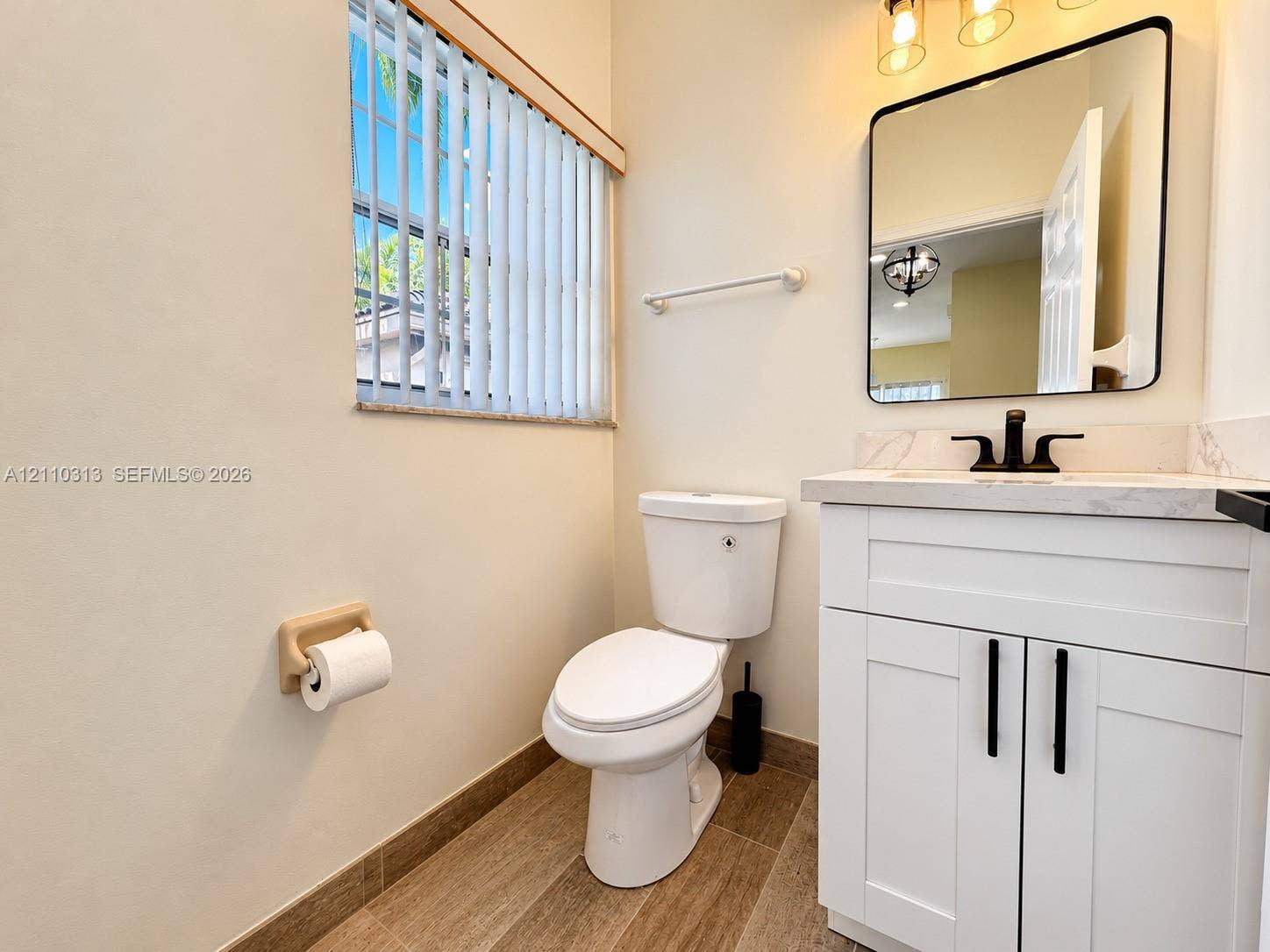17731 SW 23rd Street, Miramar, FL 33029 White shaker-style vanity with stone-top surface, matte black faucet, rectangular mirror with rounded corners, and wood-finish flooring