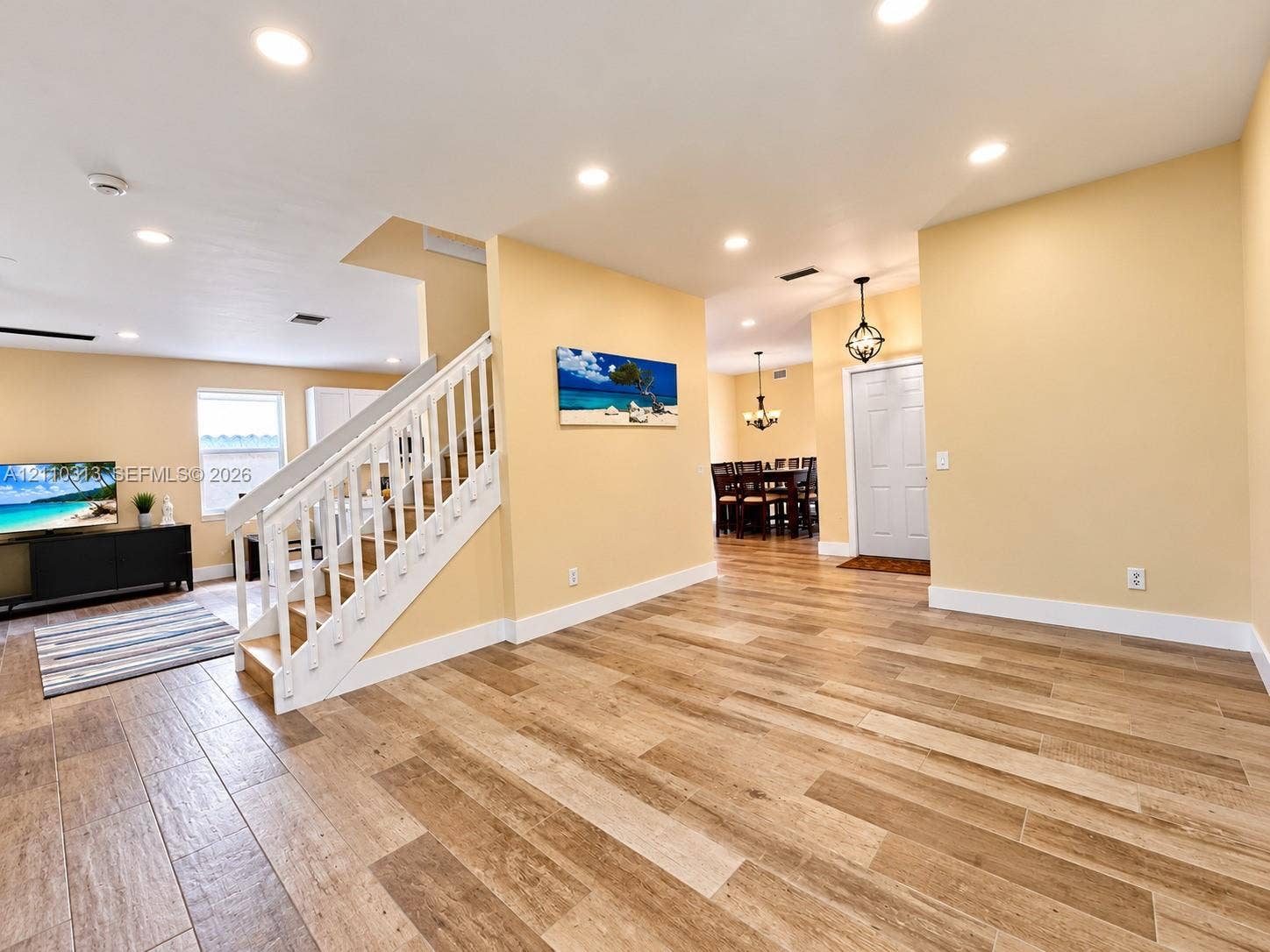 17731 SW 23rd Street, Miramar, FL 33029 Open-concept interior featuring wood-finish tile flooring, recessed ceiling lighting, and a staircase with a white balustrade
