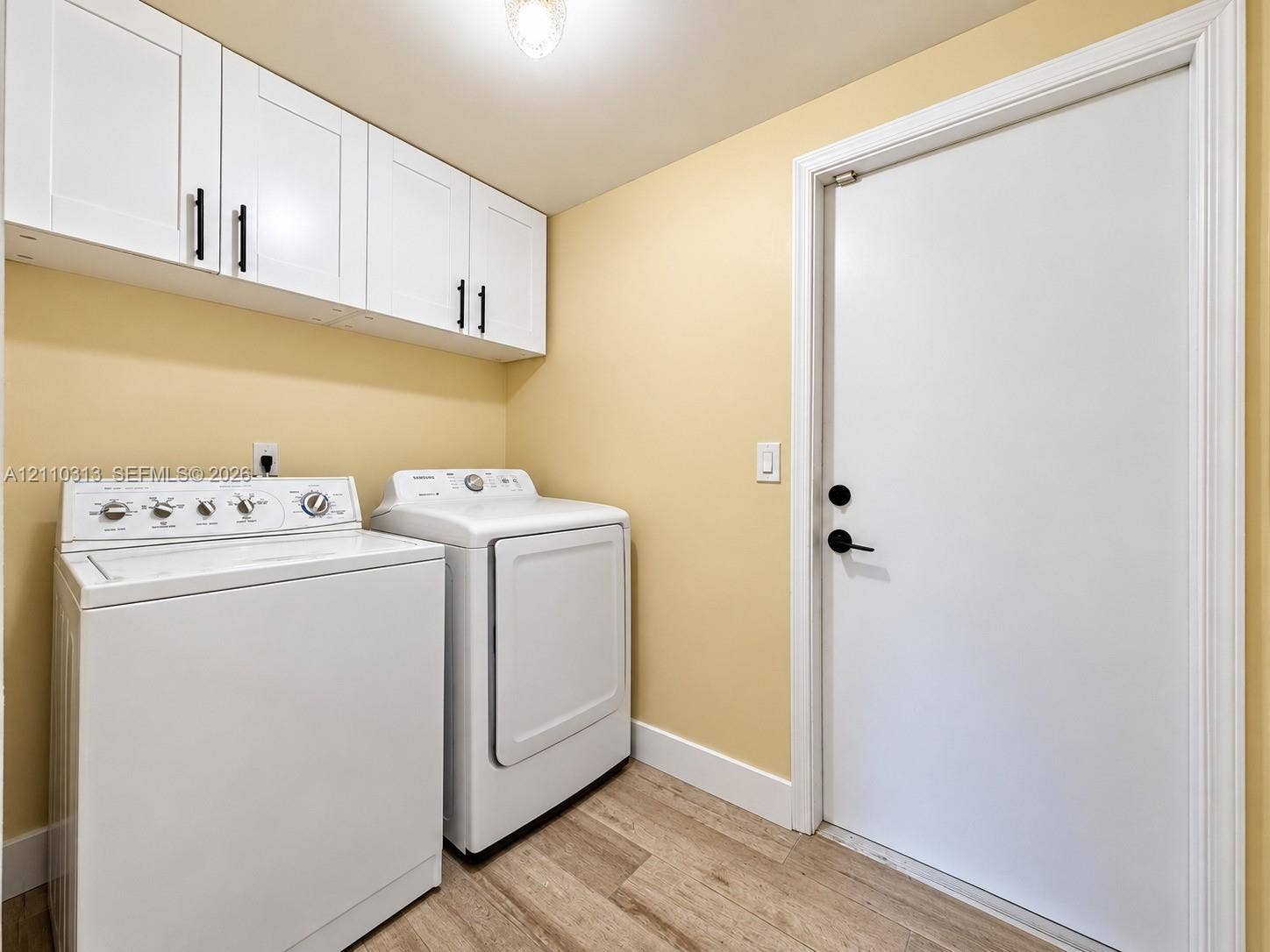 17731 SW 23rd Street, Miramar, FL 33029 Shaker-style white cabinetry with matte black hardware, wood-finish flooring, and a solid-panel door with matte black lever handle