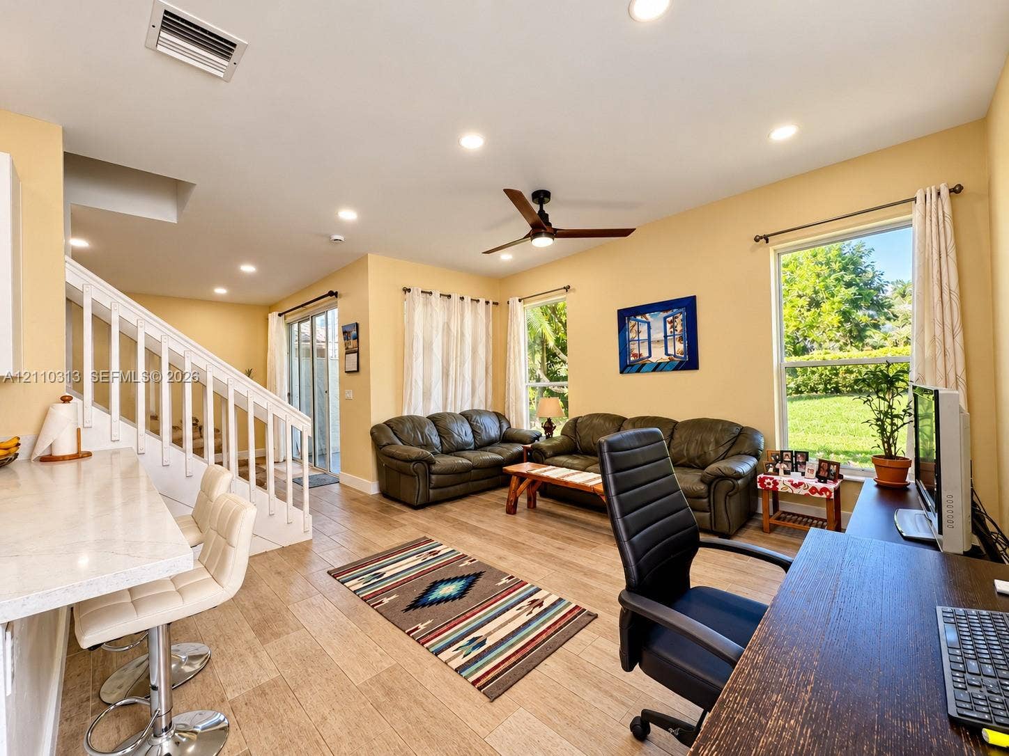 17731 SW 23rd Street, Miramar, FL 33029 Open-concept interior featuring wood-finish flooring, recessed lighting, a ceiling fan, sliding glass doors, and a breakfast bar with a stone-finish countertop