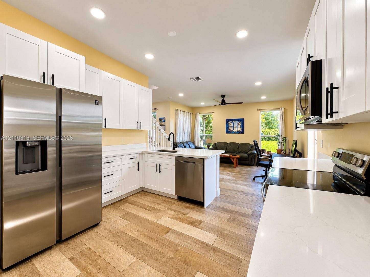 17731 SW 23rd Street, Miramar, FL 33029 Kitchen featuring white cabinetry with dark hardware, stone-finish countertops, stainless steel appliances, and wood-finish flooring
