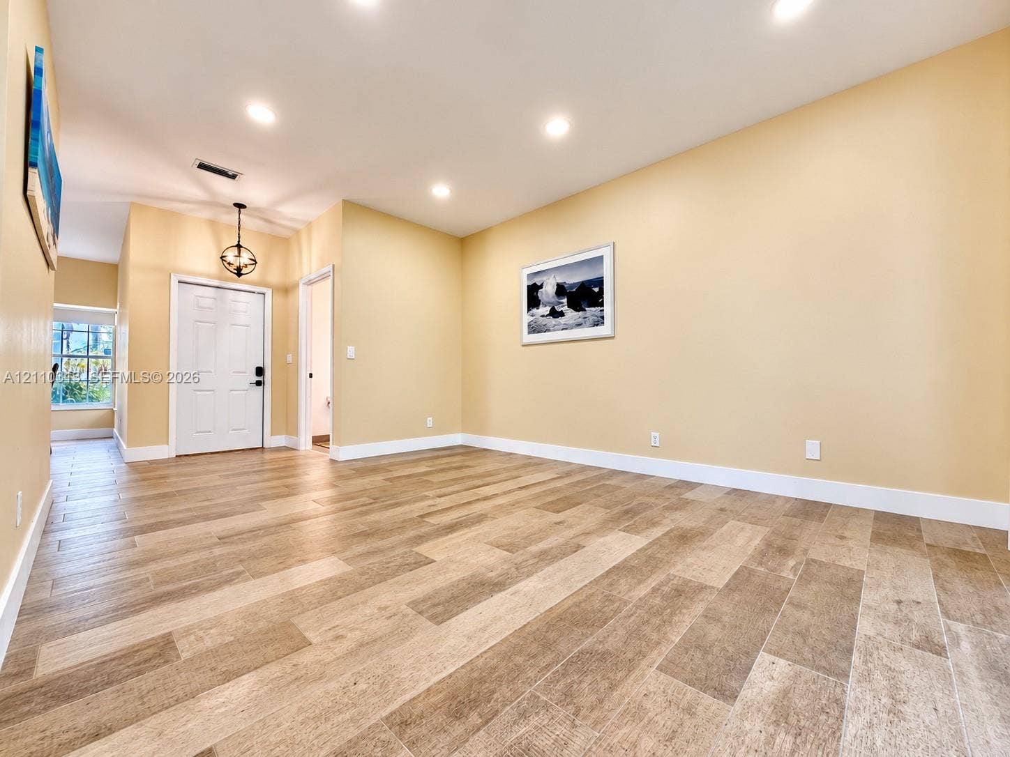 17731 SW 23rd Street, Miramar, FL 33029 Open interior space featuring wood-finish tile flooring, recessed ceiling lighting, and a six-panel entry door with a metal lantern-style pendant fixture