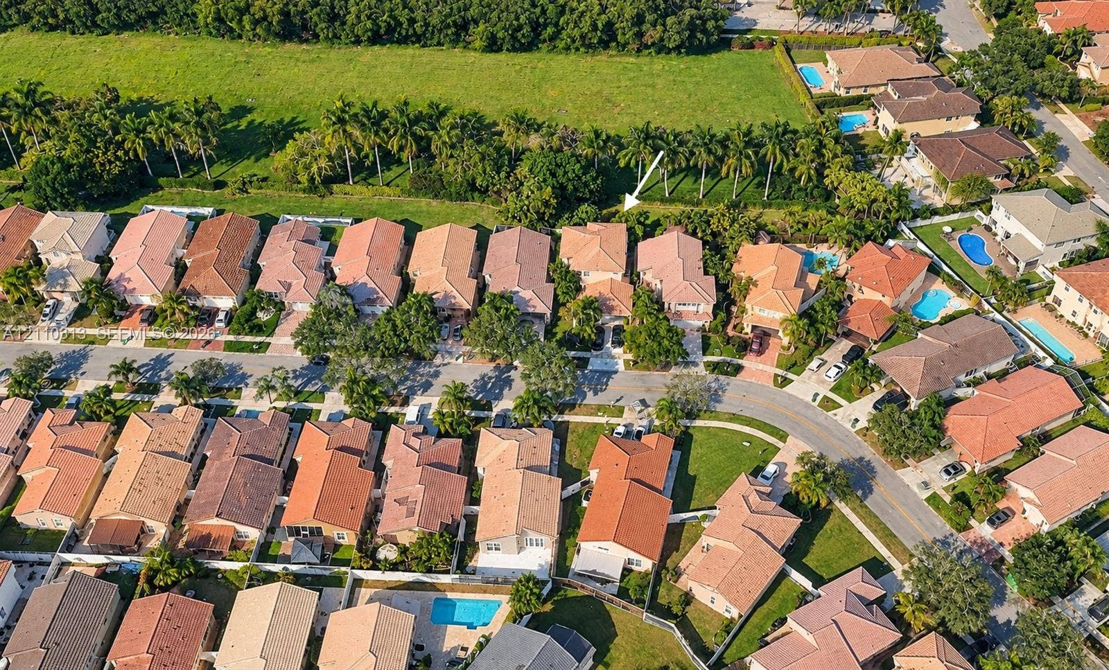 17731 SW 23rd Street, Miramar, FL 33029 Aerial perspective of a residential property featuring a tiled roof, multi-car garage, perimeter fencing, and mature palm trees