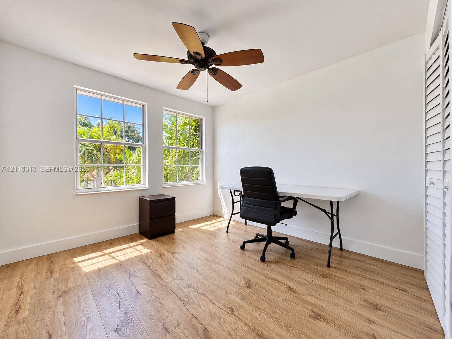 17731 SW 23rd Street, Miramar, FL 33029 Wood-finish flooring, dual grid-pattern windows, ceiling fan with wood-tone blades, and louvered bi-fold closet doors