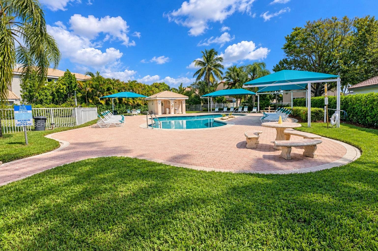 17731 SW 23rd Street, Miramar, FL 33029 Community pool featuring a paved deck, permanent shaded structures, built-in masonry seating, and manicured landscaping