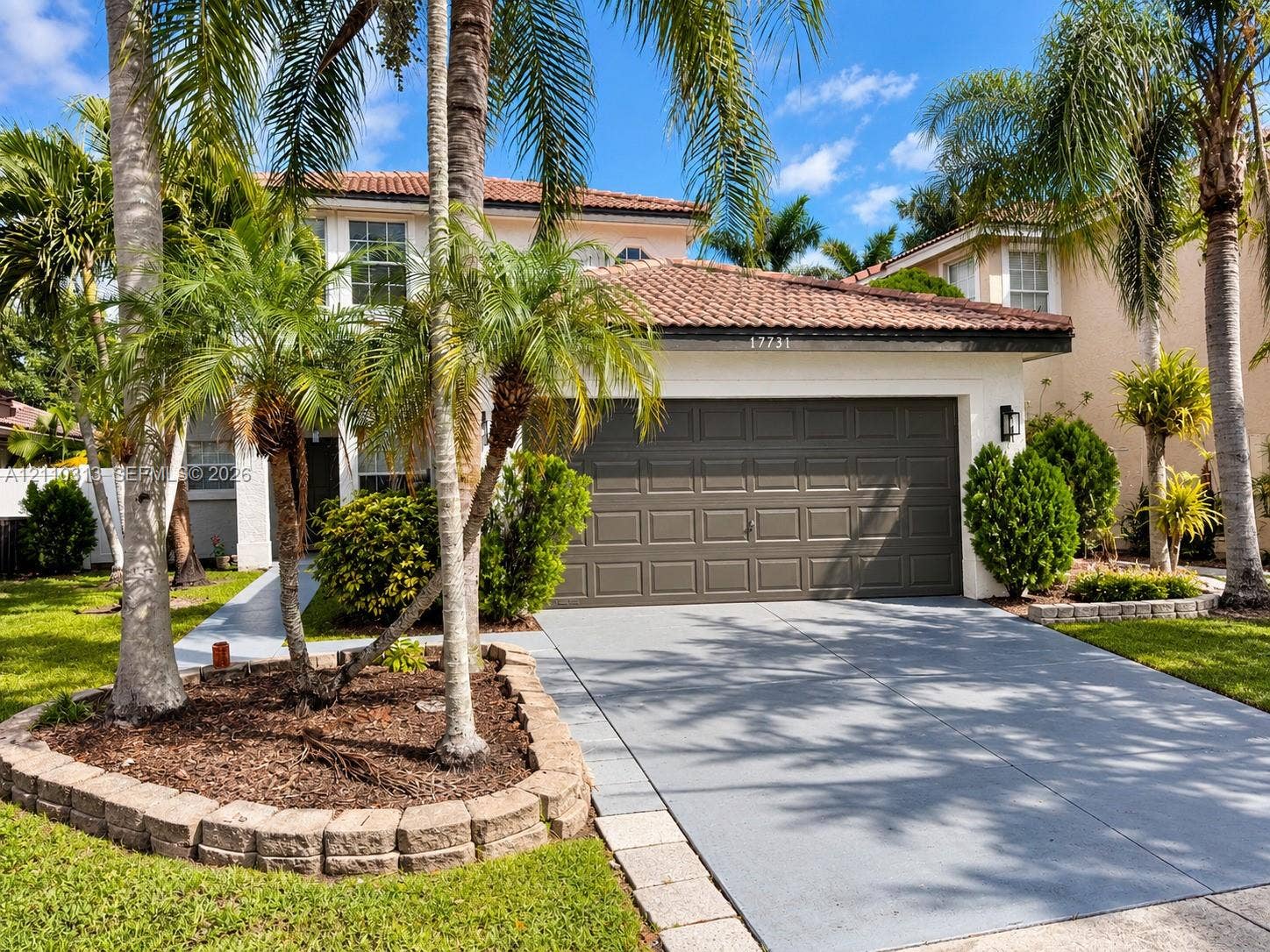 17731 SW 23rd Street, Miramar, FL 33029 Stucco exterior featuring a clay tile roof, two-car garage, concrete driveway, and stone-bordered landscaping beds