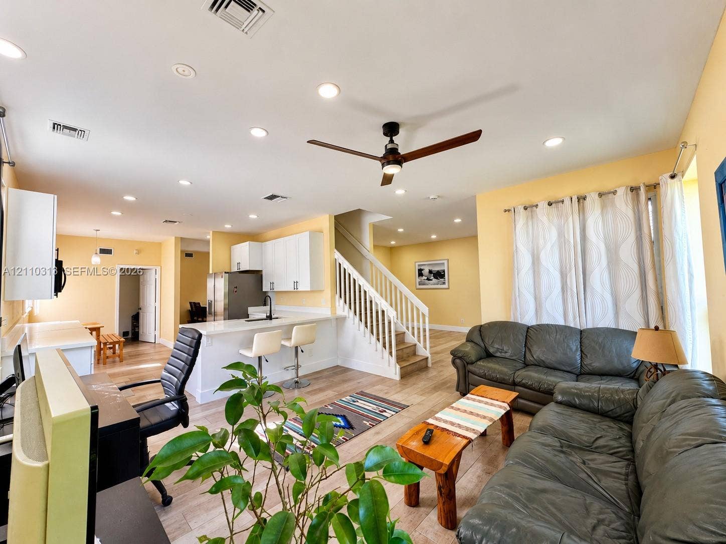 17731 SW 23rd Street, Miramar, FL 33029 Open-concept interior featuring wood-finish flooring, recessed lighting, a modern kitchen with white cabinetry, a breakfast bar, and a staircase with a white railing