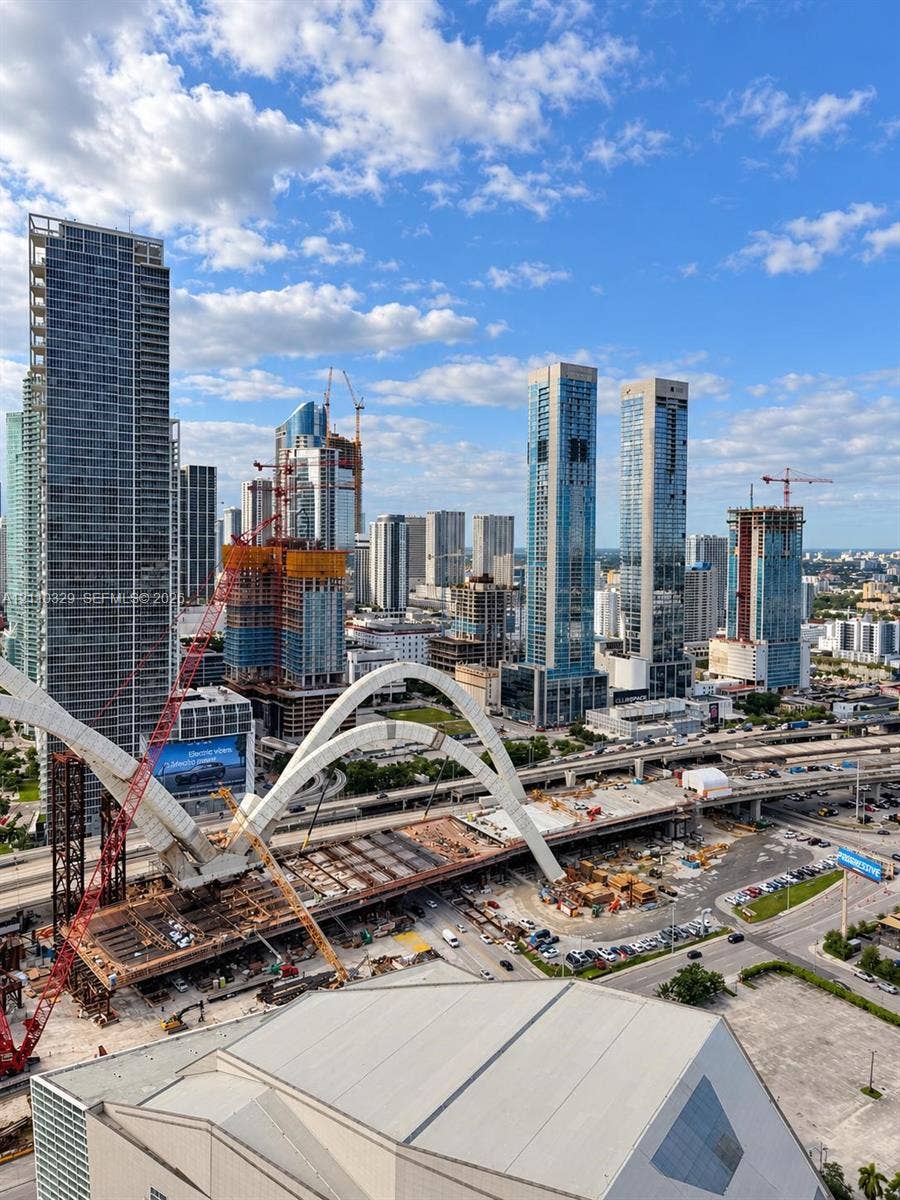 Panoramic urban landscape featuring a high-rise skyline, architectural arched bridge infrastructure, and elevated highway networks