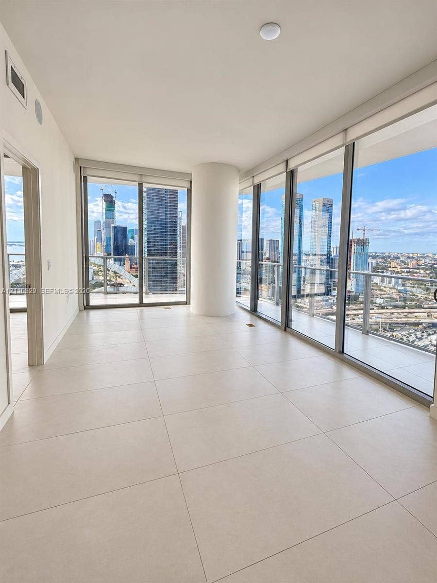 Floor-to-ceiling glass windows, ceramic tile flooring, wraparound balcony access, and structural column