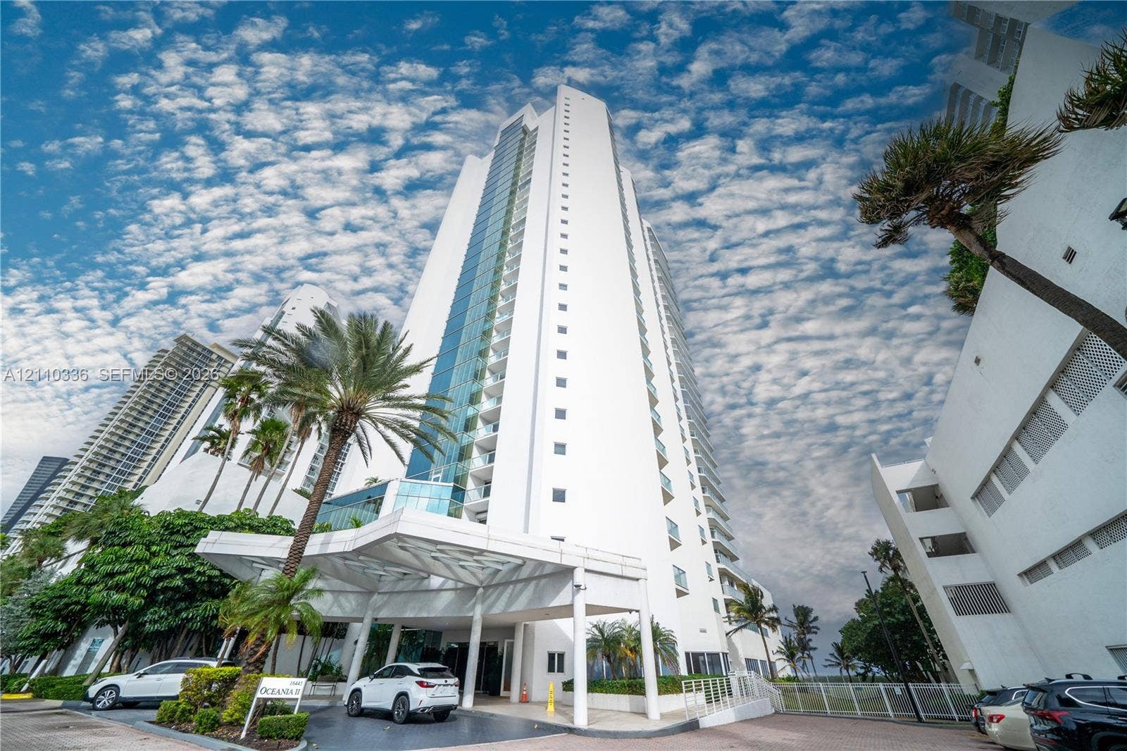 16445 Collins Avenue, #WS-7B, Sunny Isles Beach, Sunny Isles Beach, FL 33160 High-rise residential tower featuring a glass-paneled facade, private balconies, and a porte-cochre entry with structural columns