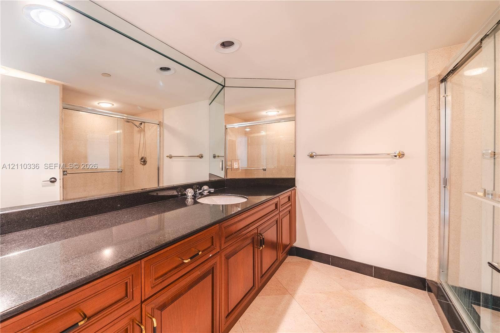 16445 Collins Avenue, #WS-7B, Sunny Isles Beach, Sunny Isles Beach, FL 33160 Full-width vanity featuring dark stone-finish countertop, undermount sink, recessed lighting, expansive wall-to-wall mirror, and wood-finish cabinetry