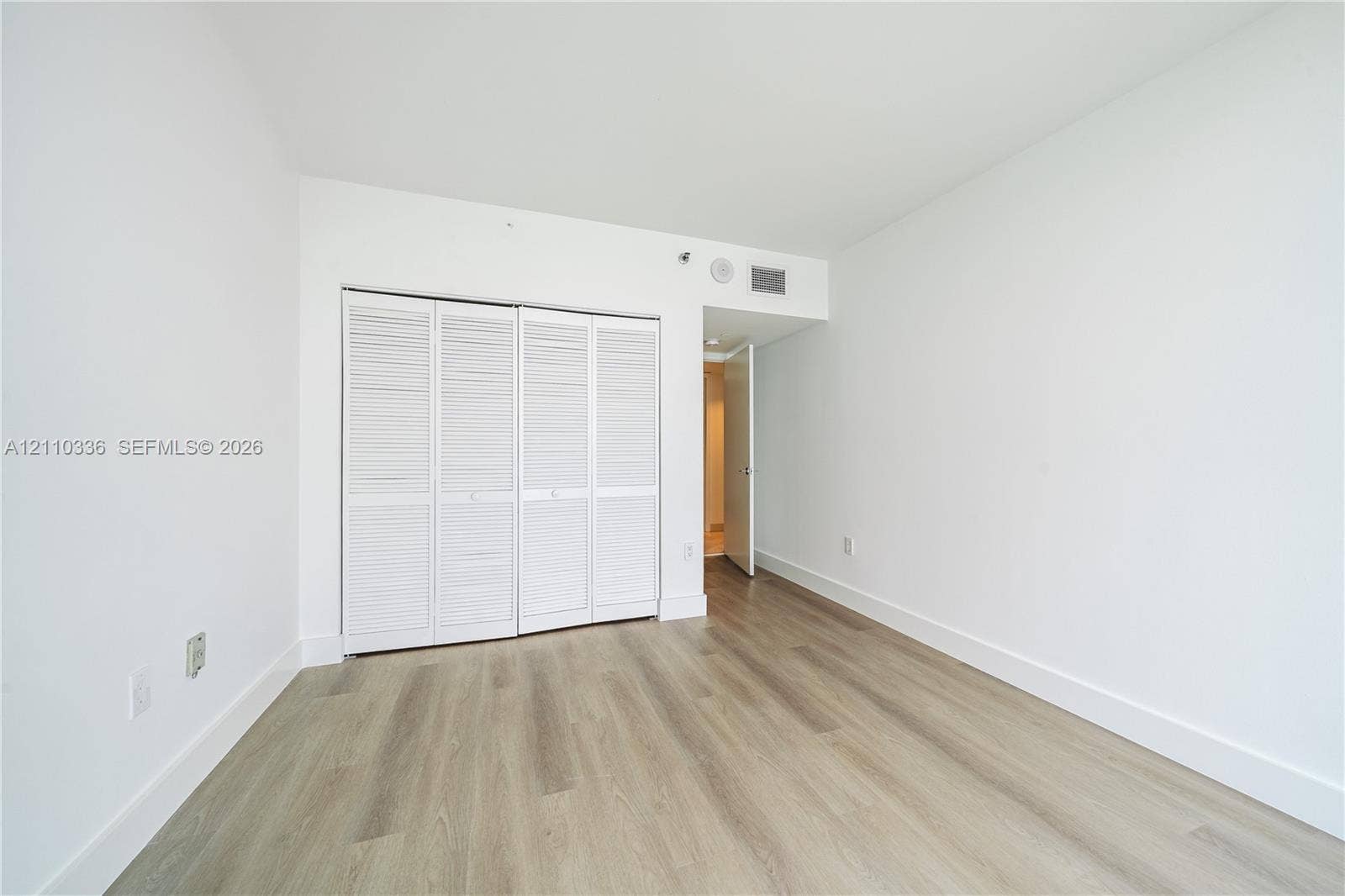 16445 Collins Avenue, #WS-7B, Sunny Isles Beach, Sunny Isles Beach, FL 33160 Room featuring wood-finish flooring, white walls, and a closet with bifold louvered doors
