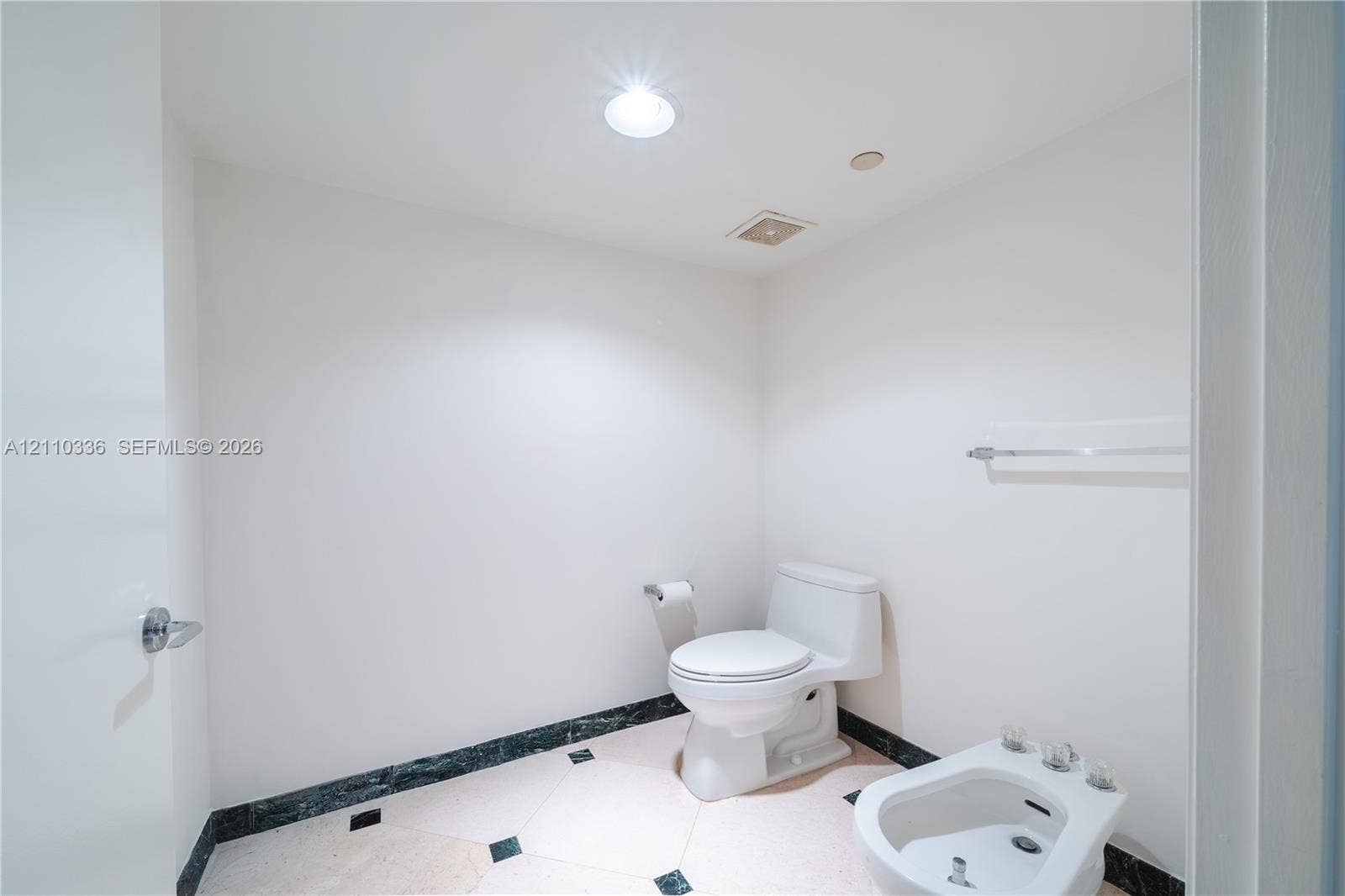 16445 Collins Avenue, #WS-7B, Sunny Isles Beach, Sunny Isles Beach, FL 33160 Restroom featuring a dual-piece toilet, porcelain bidet, stone-finish tile flooring with inlaid accents, and a coordinating stone baseboard