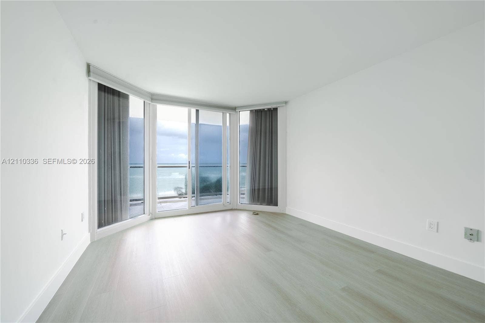 16445 Collins Avenue, #WS-7B, Sunny Isles Beach, Sunny Isles Beach, FL 33160 Floor-to-ceiling windows, sliding glass door, wood-finish flooring, and balcony access with water backdrop