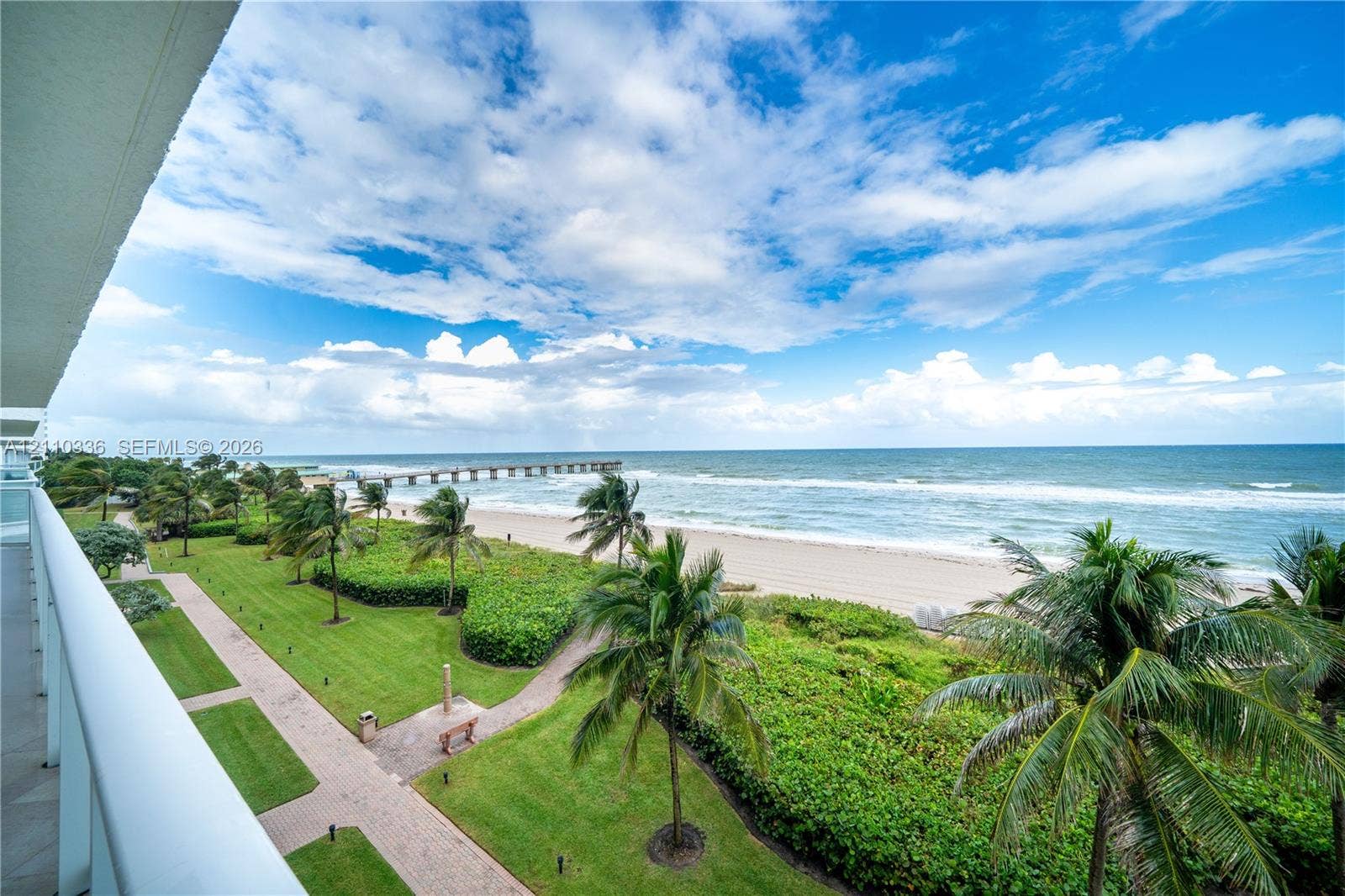 16445 Collins Avenue, #WS-7B, Sunny Isles Beach, Sunny Isles Beach, FL 33160 Elevated balcony overlooking coastal frontage featuring palm trees, manicured green space, paved walkways, and a pier extending into the ocean