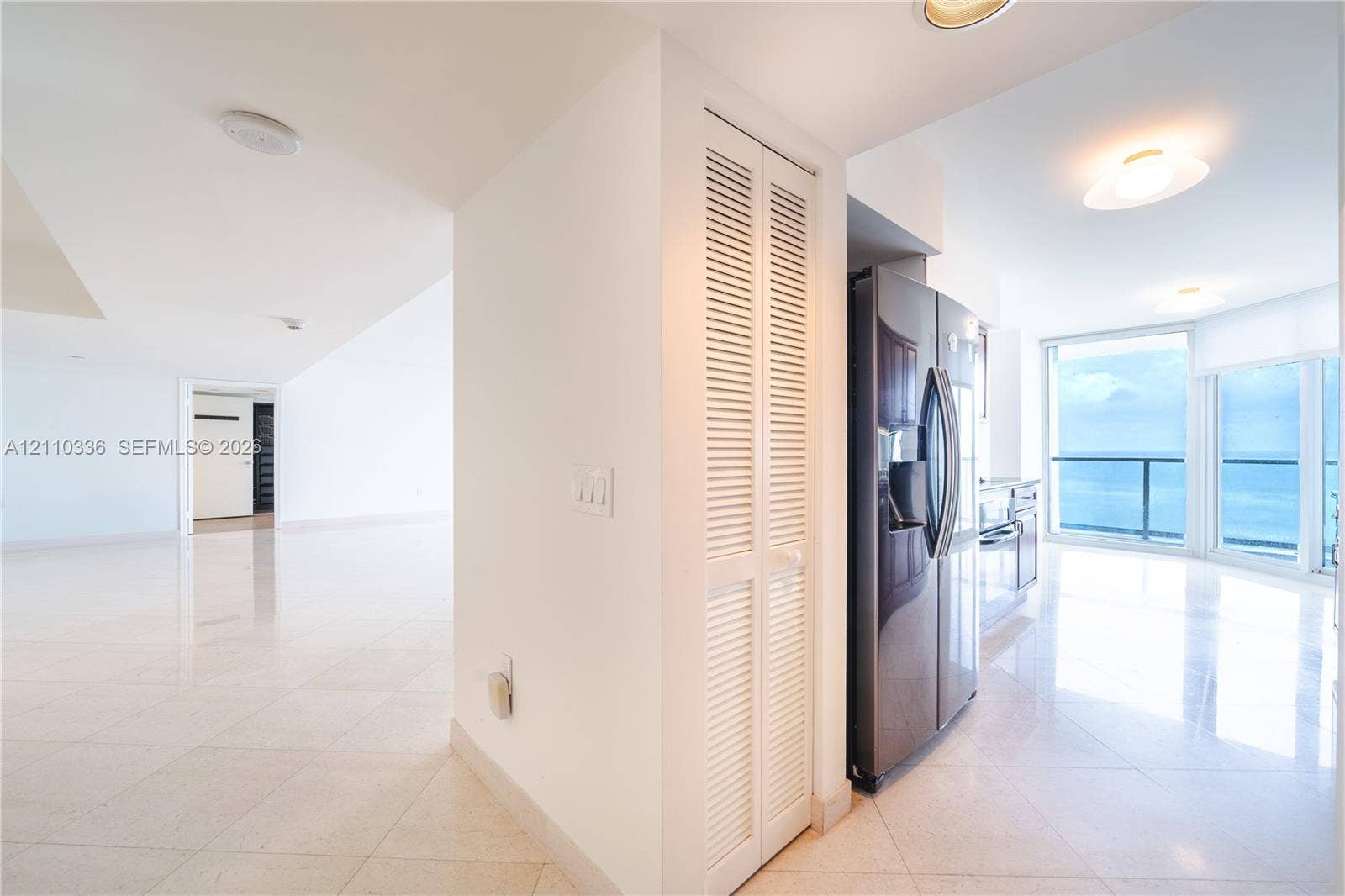 16445 Collins Avenue, #WS-7B, Sunny Isles Beach, Sunny Isles Beach, FL 33160 Interior space featuring polished stone flooring, recessed lighting, white louvered closet doors, stainless steel refrigerator, and floor-to-ceiling windows