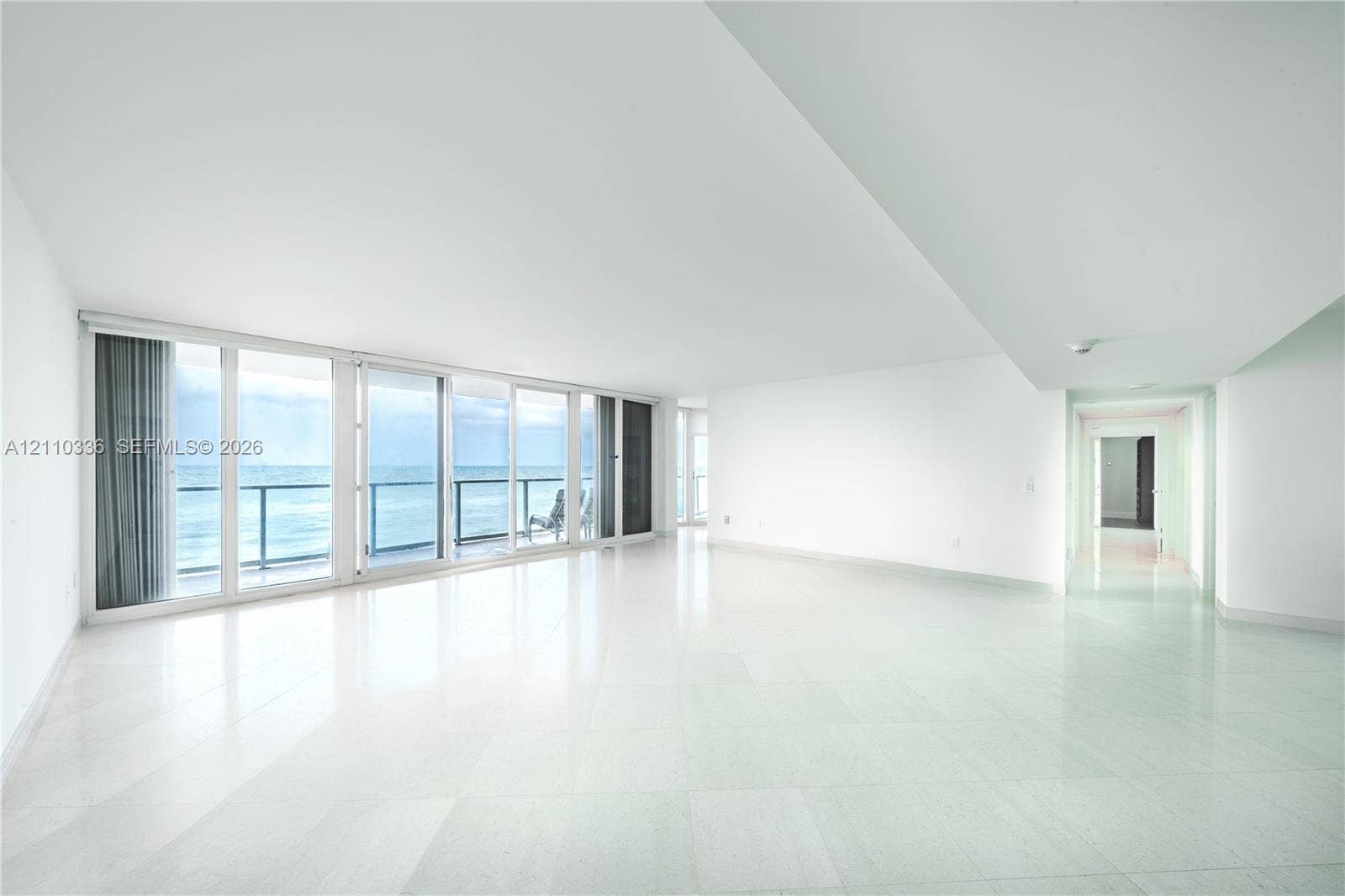 16445 Collins Avenue, #WS-7B, Sunny Isles Beach, Sunny Isles Beach, FL 33160 Open-concept interior featuring polished stone flooring, floor-to-ceiling glass sliding doors, and a private balcony with metal railing