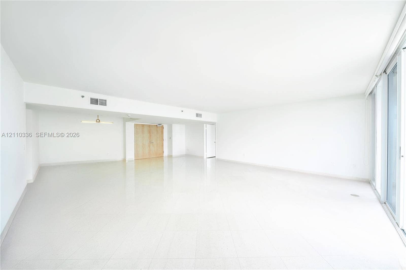 16445 Collins Avenue, #WS-7B, Sunny Isles Beach, Sunny Isles Beach, FL 33160 Expansive open-concept interior featuring large-format tile flooring, floor-to-ceiling glass sliding doors, and a linear pendant light fixture