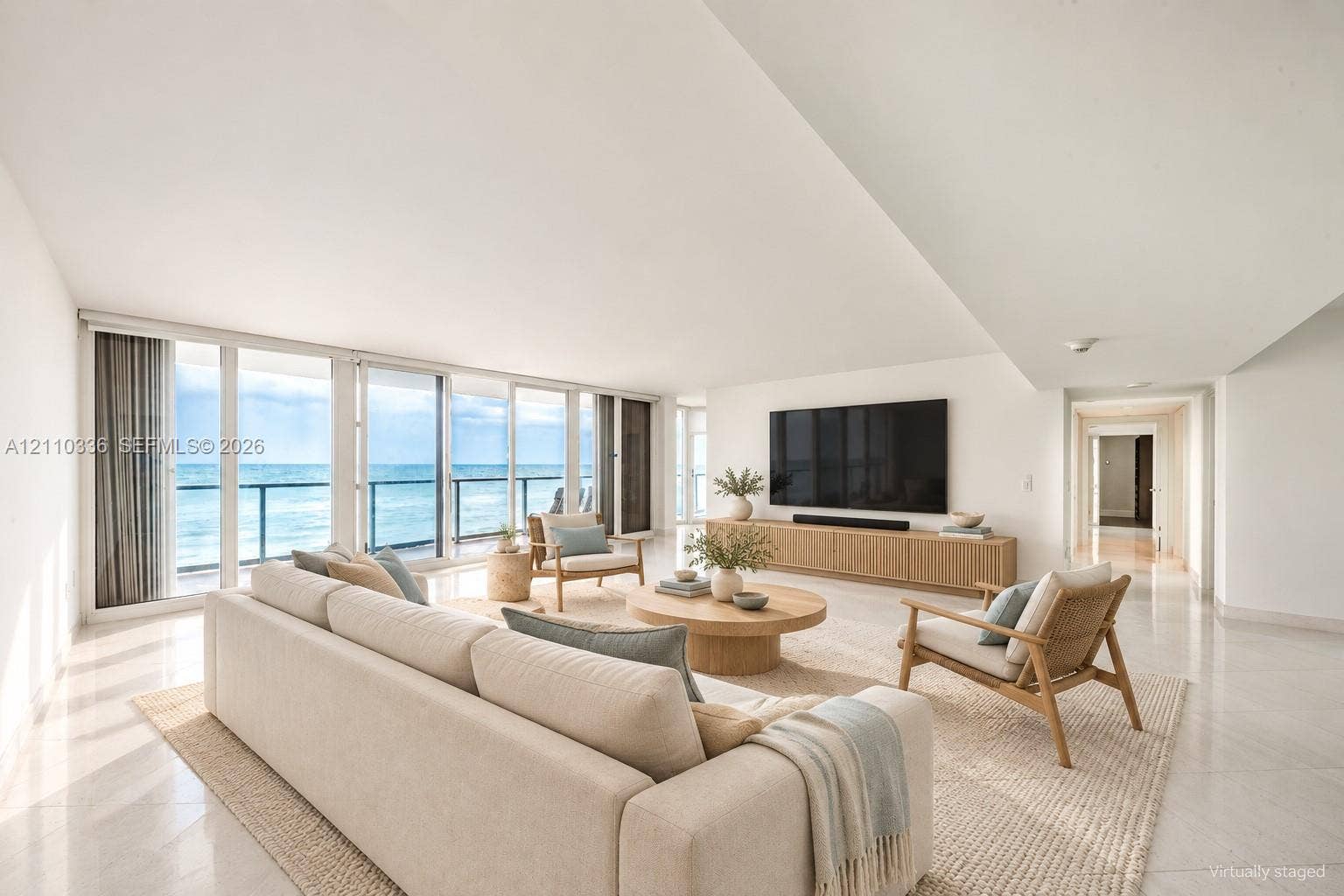 16445 Collins Avenue, #WS-7B, Sunny Isles Beach, Sunny Isles Beach, FL 33160 Expansive living space featuring floor-to-ceiling glass panel doors, a balcony with a metal railing, polished stone flooring, and a built-in wood-finish media console