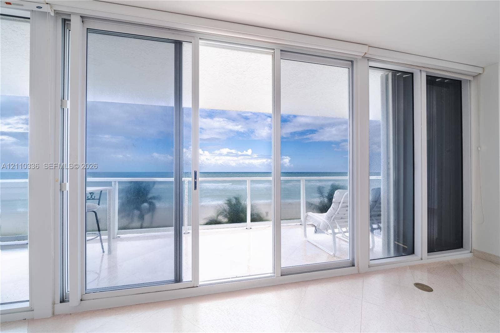 16445 Collins Avenue, #WS-7B, Sunny Isles Beach, Sunny Isles Beach, FL 33160 Floor-to-ceiling sliding glass panels, balcony with glass railing, stone flooring, and expansive ocean scenery