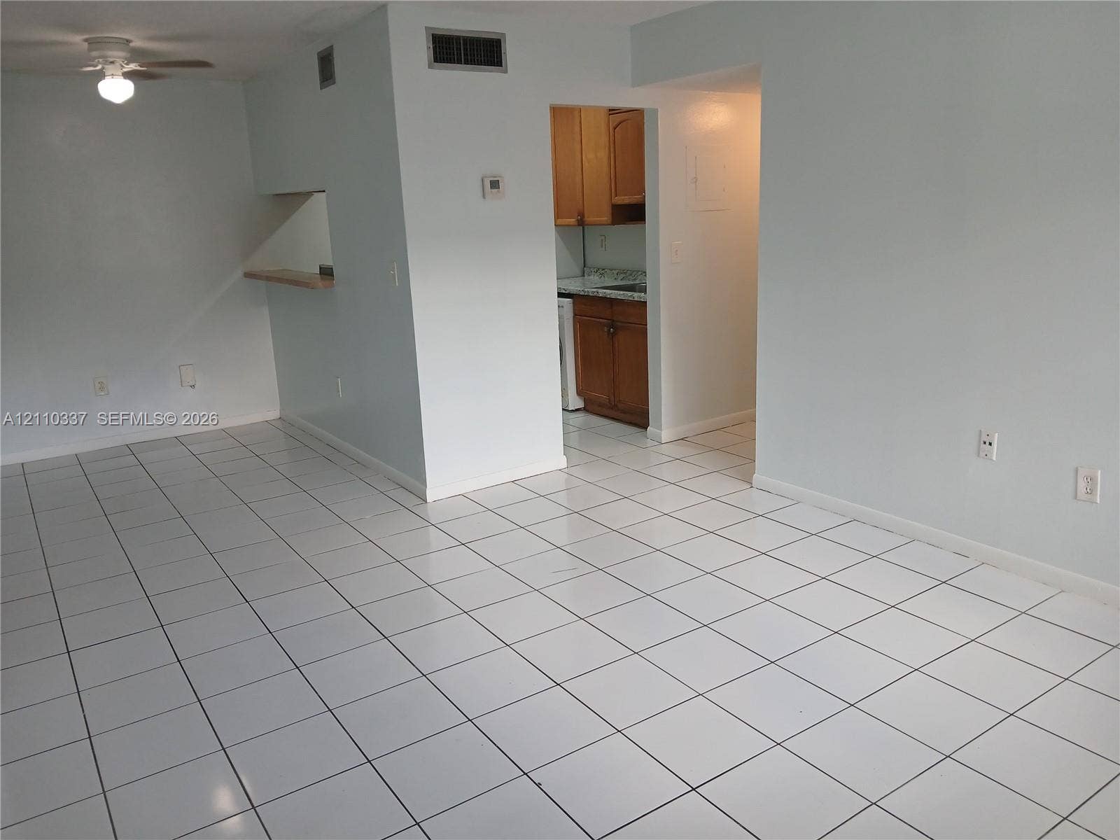 Interior space featuring ceramic tile flooring, a pass-through opening to the kitchen, and a ceiling-mounted light fixture