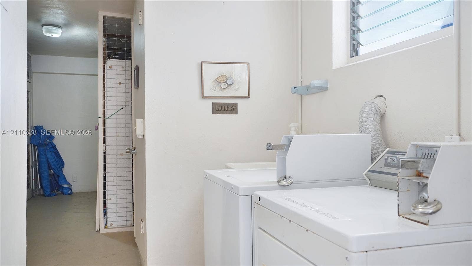 Laundry area featuring a louvered window, built-in wire shelving, and overhead lighting