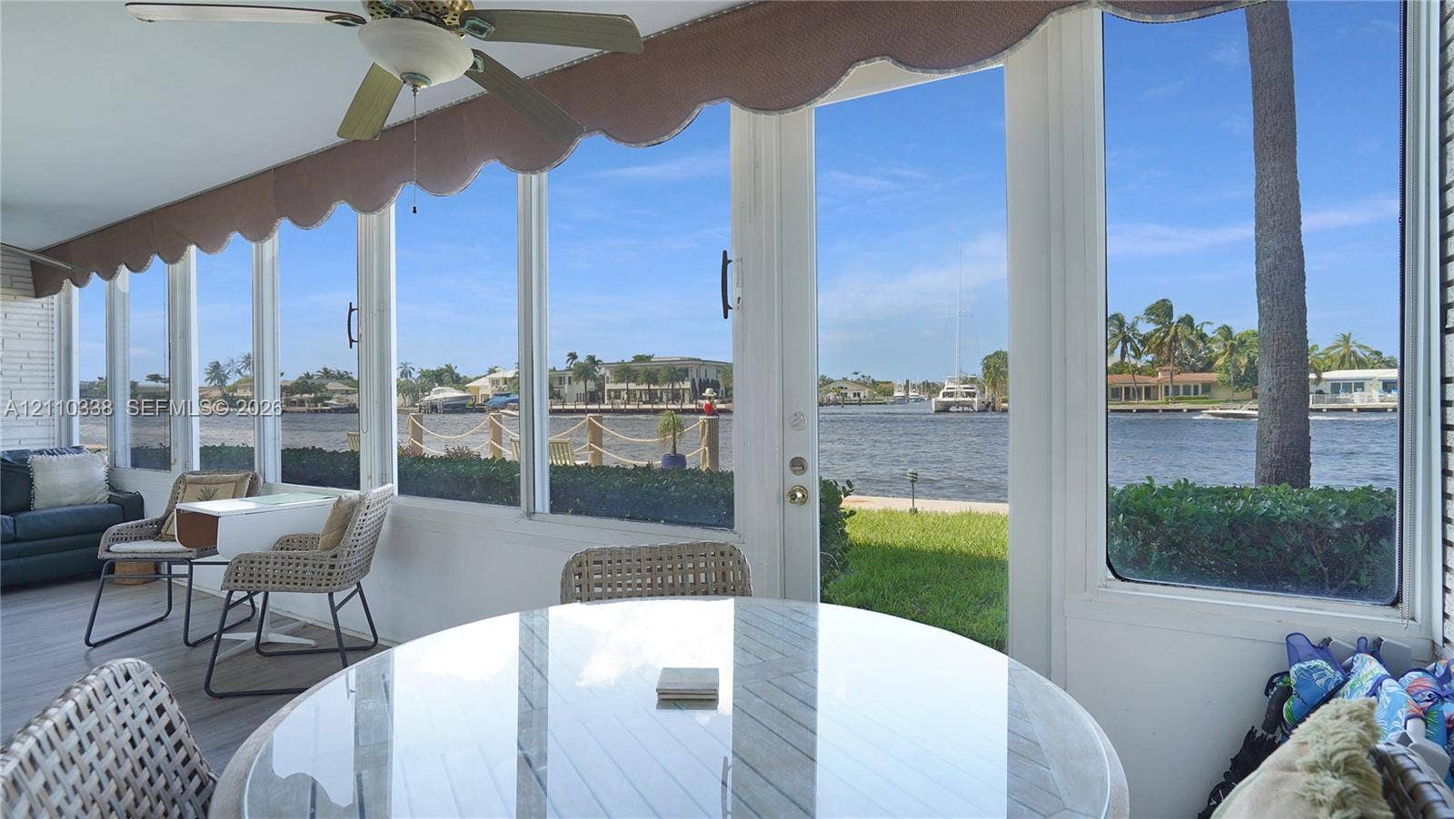 Enclosed porch featuring floor-to-ceiling windows, waterfront exposure, ceiling fan, and painted masonry walls