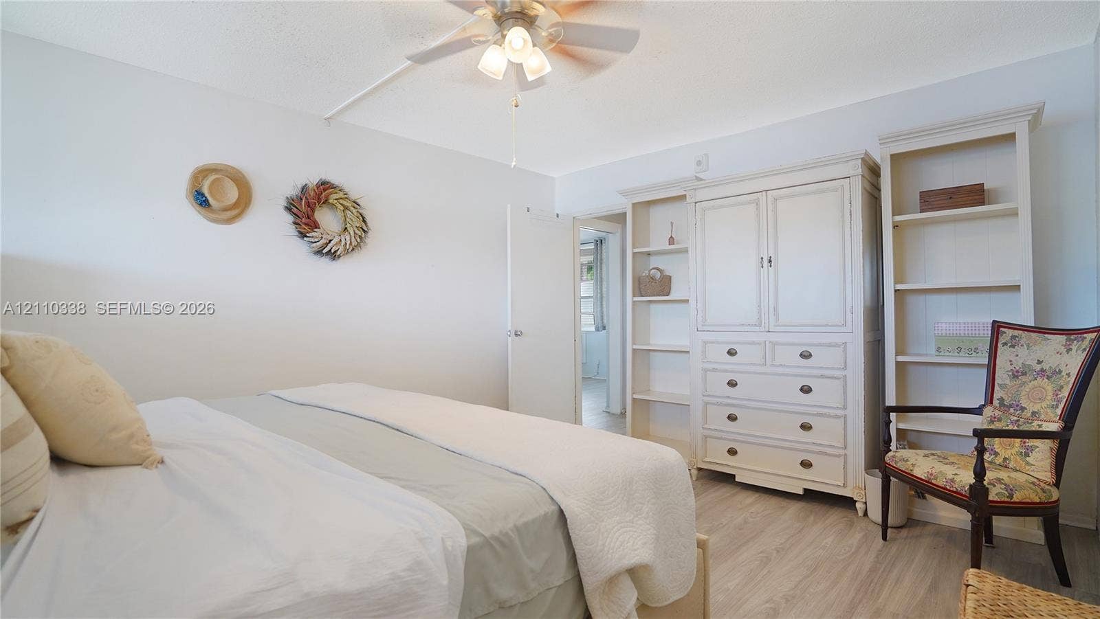 Built-in floor-to-ceiling cabinetry, wood-finish flooring, and a ceiling fan with integrated light fixture
