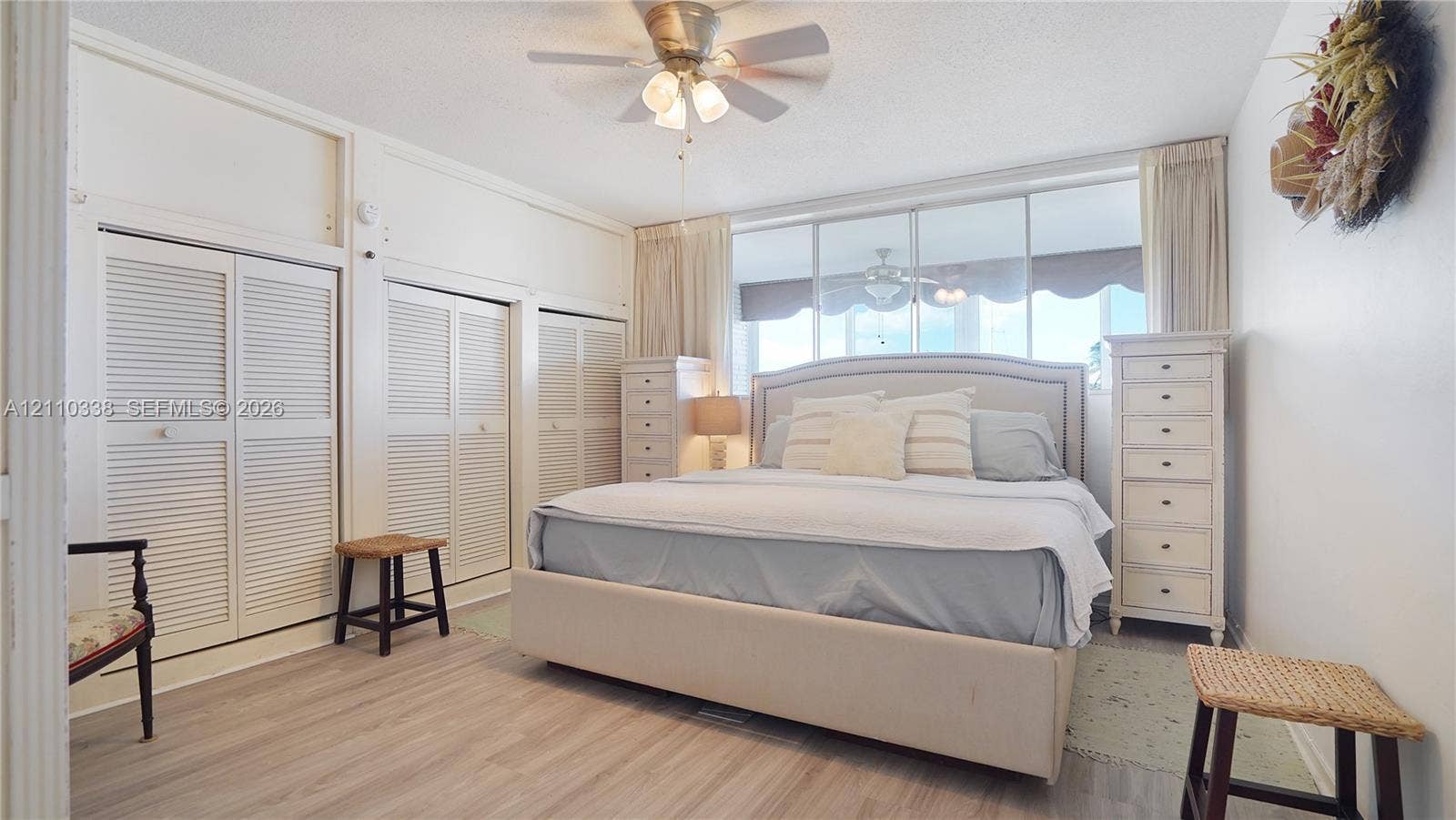 Wood-finish flooring, multi-panel louvered closet doors, ceiling fan with integrated lighting, and expansive wall-to-wall glass windows WATER VIEWS!