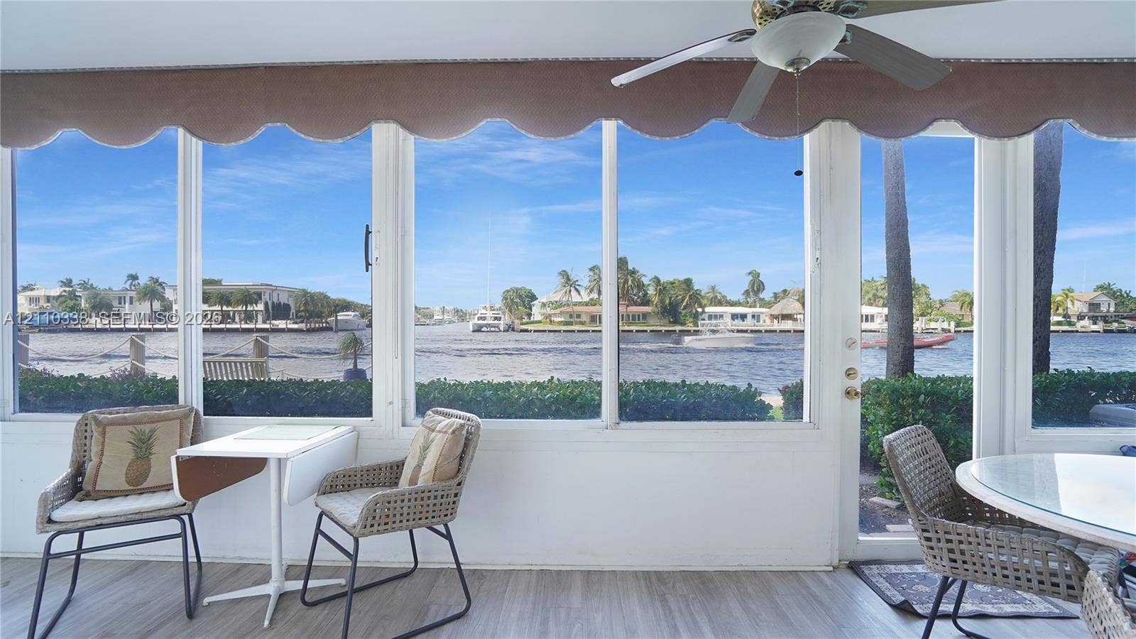 featuring expansive glass windows, wood-finish flooring, and a ceiling-mounted fan
