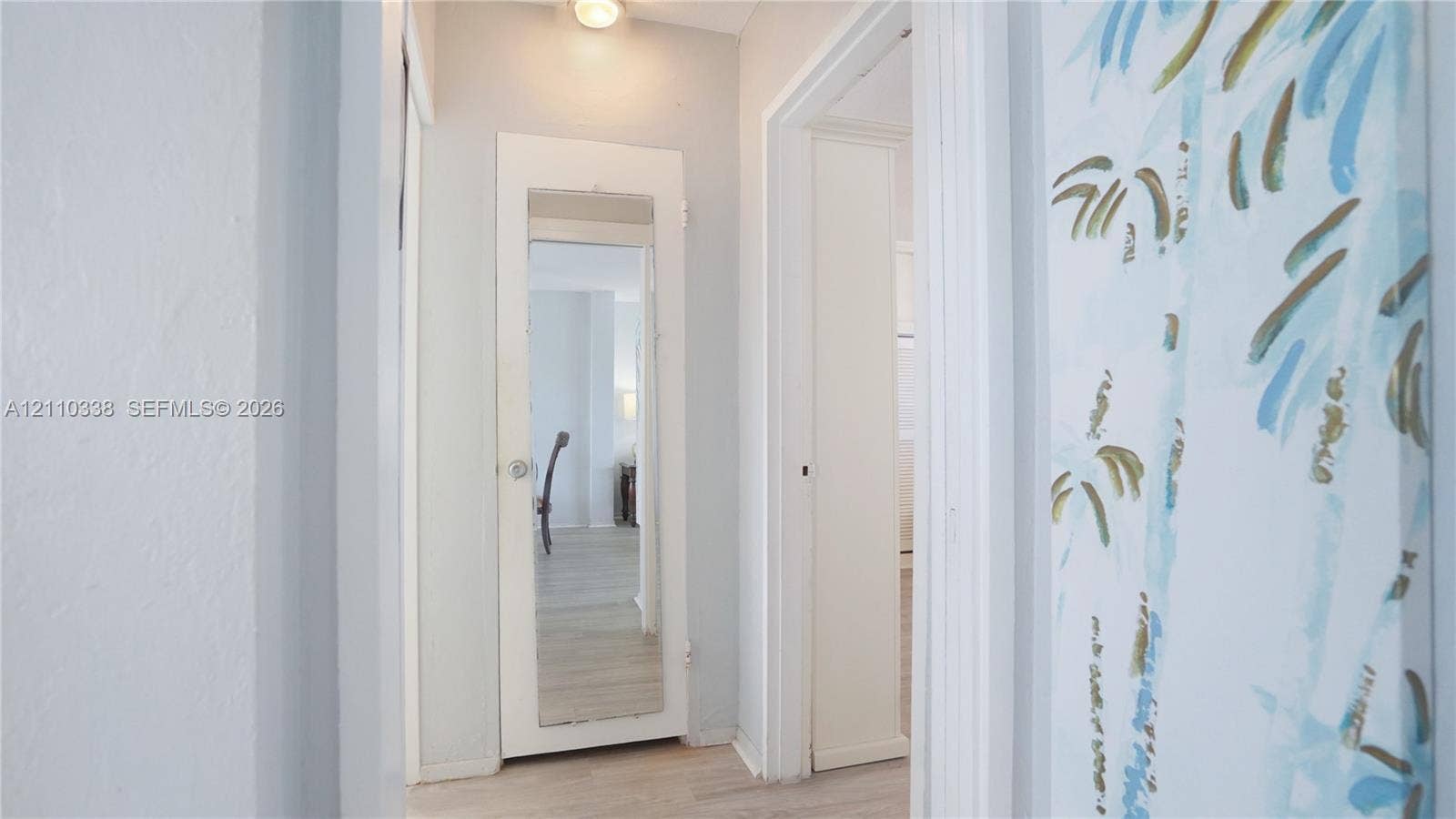 Hallway featuring light-toned flooring, a mirrored door, and neutral wall paint