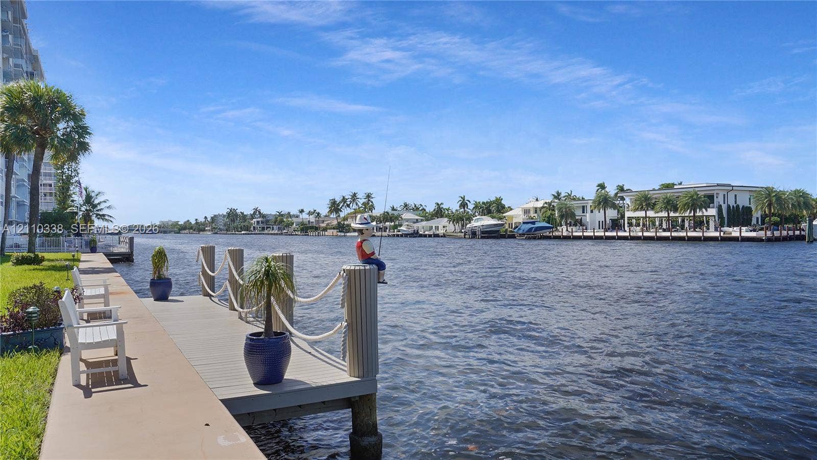 Concrete seawall bulkhead with an extended composite dock, rope railings, and manicured turf grass