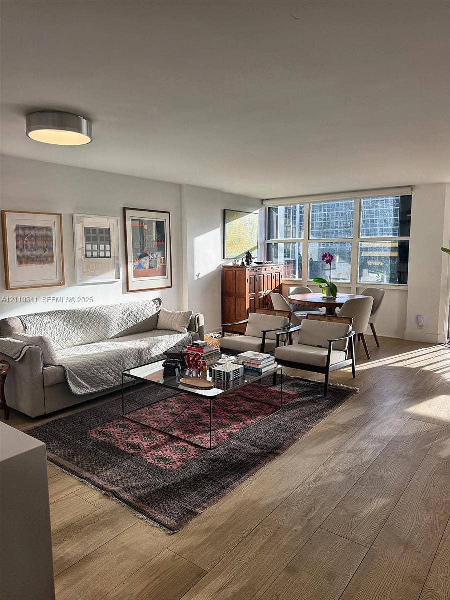Living area featuring wood-finish flooring, floor-to-ceiling windows, and a flush-mount ceiling light