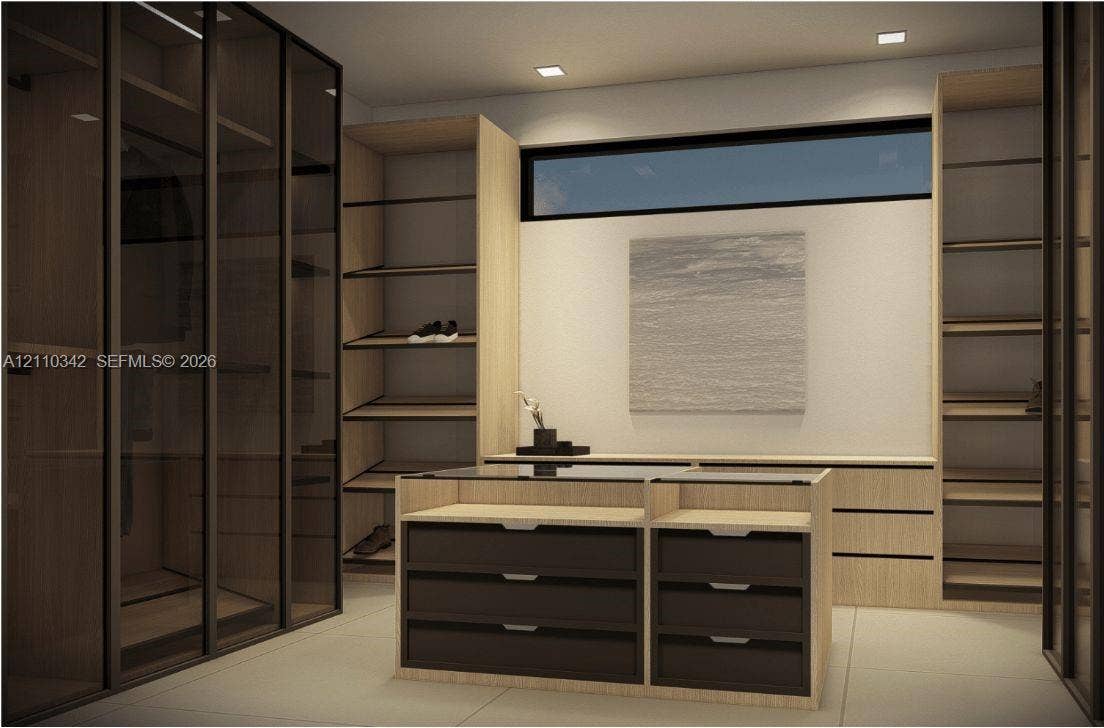 1030 NW 9th Court, Miami, FL 33136 Custom cabinetry featuring wood-finish shelving, glass-front wardrobe enclosures, a central island with a glass top and matte-finish drawers, and recessed lighting, accented by a horizontal clerestory window