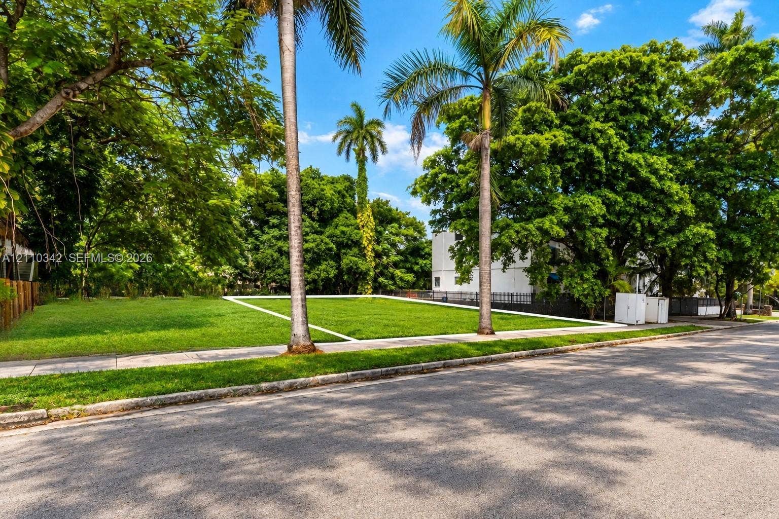 1030 NW 9th Court, Miami, FL 33136 Cleared parcel featuring a grass lawn, mature palm trees, and existing concrete sidewalk
