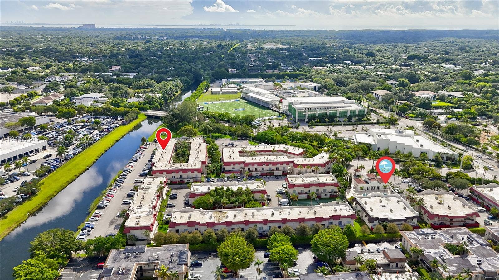 8600 SW 67th Avenue, #905, Pinecrest, Pinecrest, FL 33156 Aerial perspective of a multi-building residential complex featuring white stucco facades, terra cotta roof accents, mature landscaping, and an adjacent canal